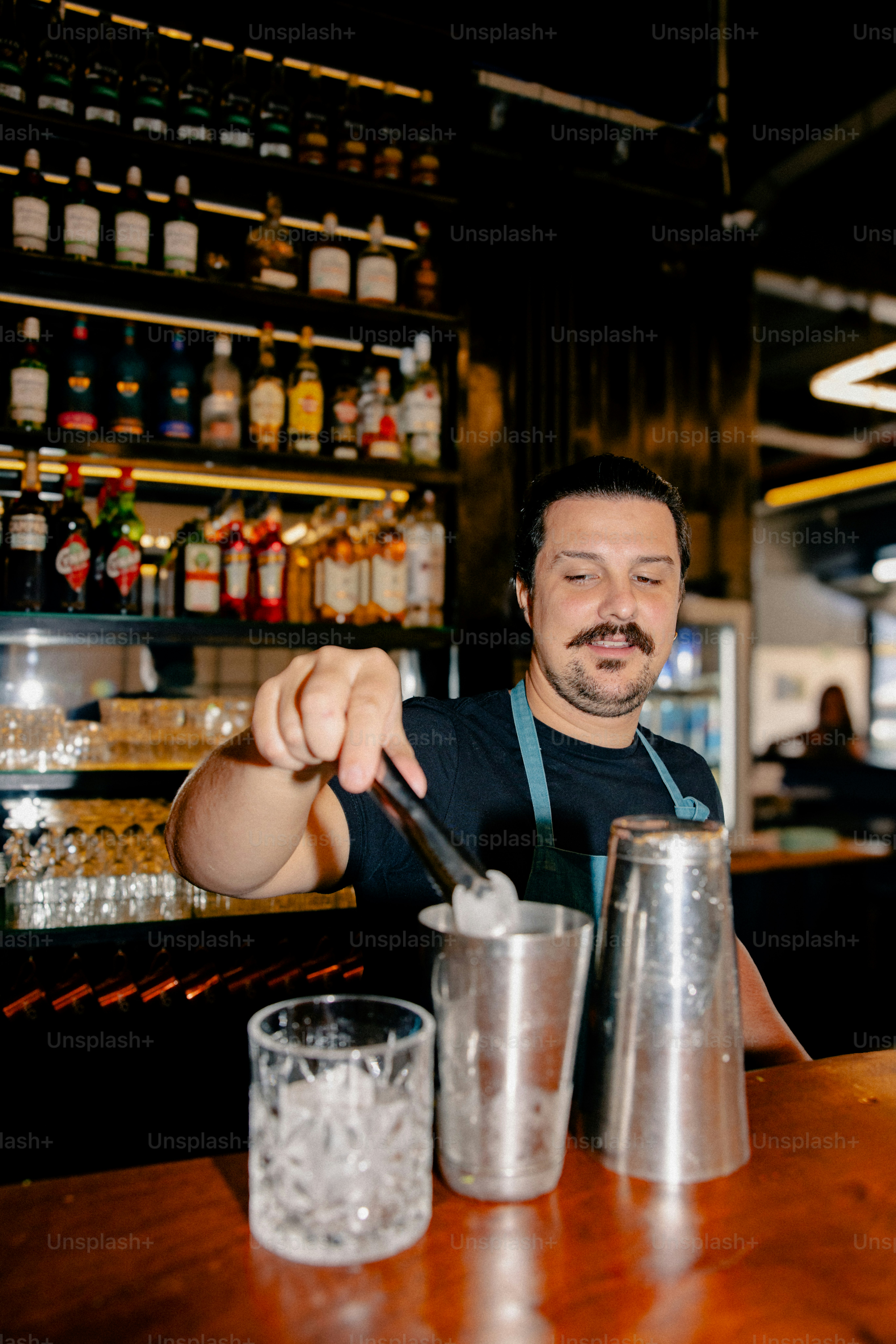 A bartender adds garnish to a cocktail. photo – Bar Image on Unsplash