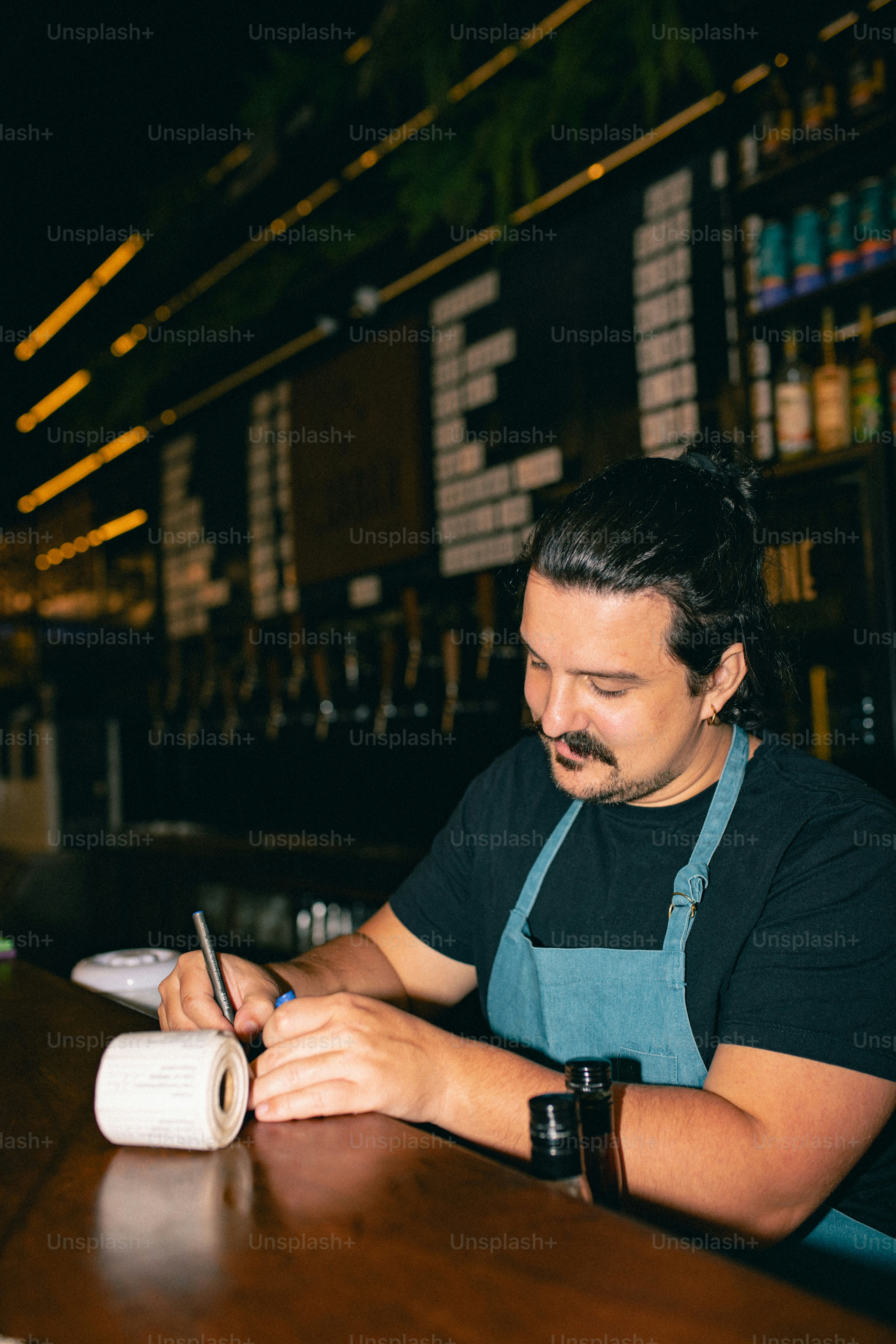 Bartender writing on a label at the bar.