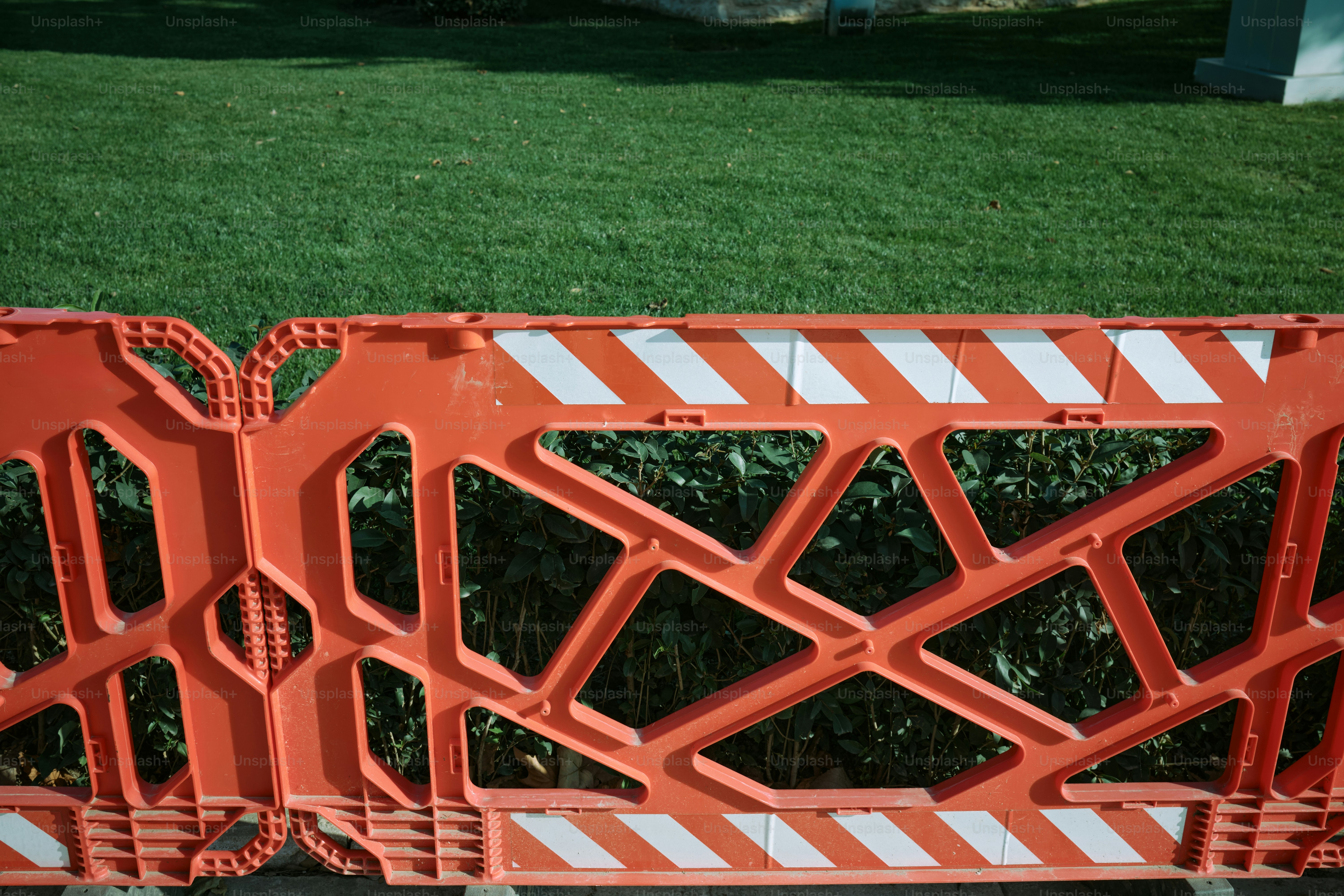 Orange traffic barrier is placed in front of grass.