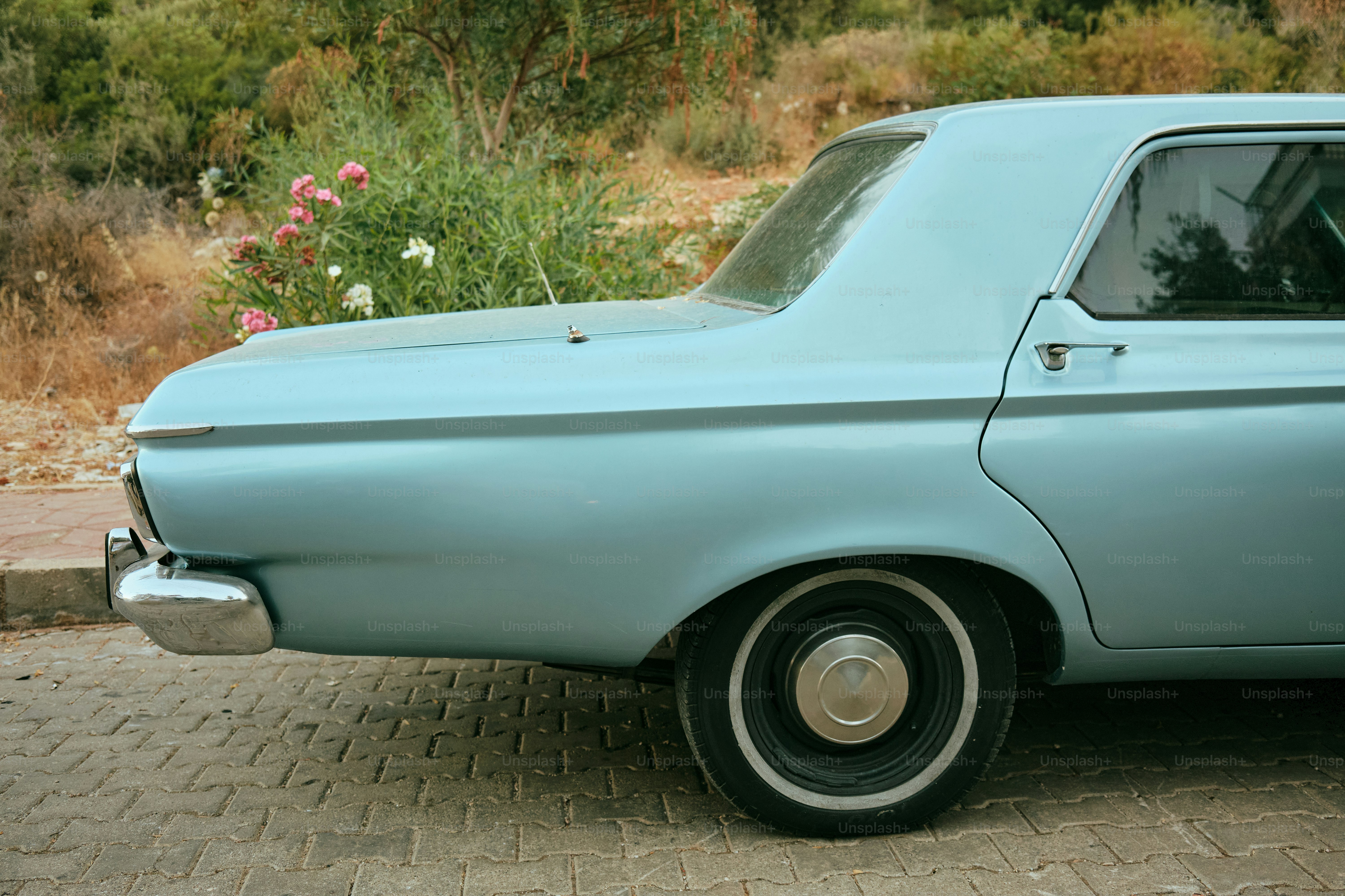 An old blue car is parked outdoors.