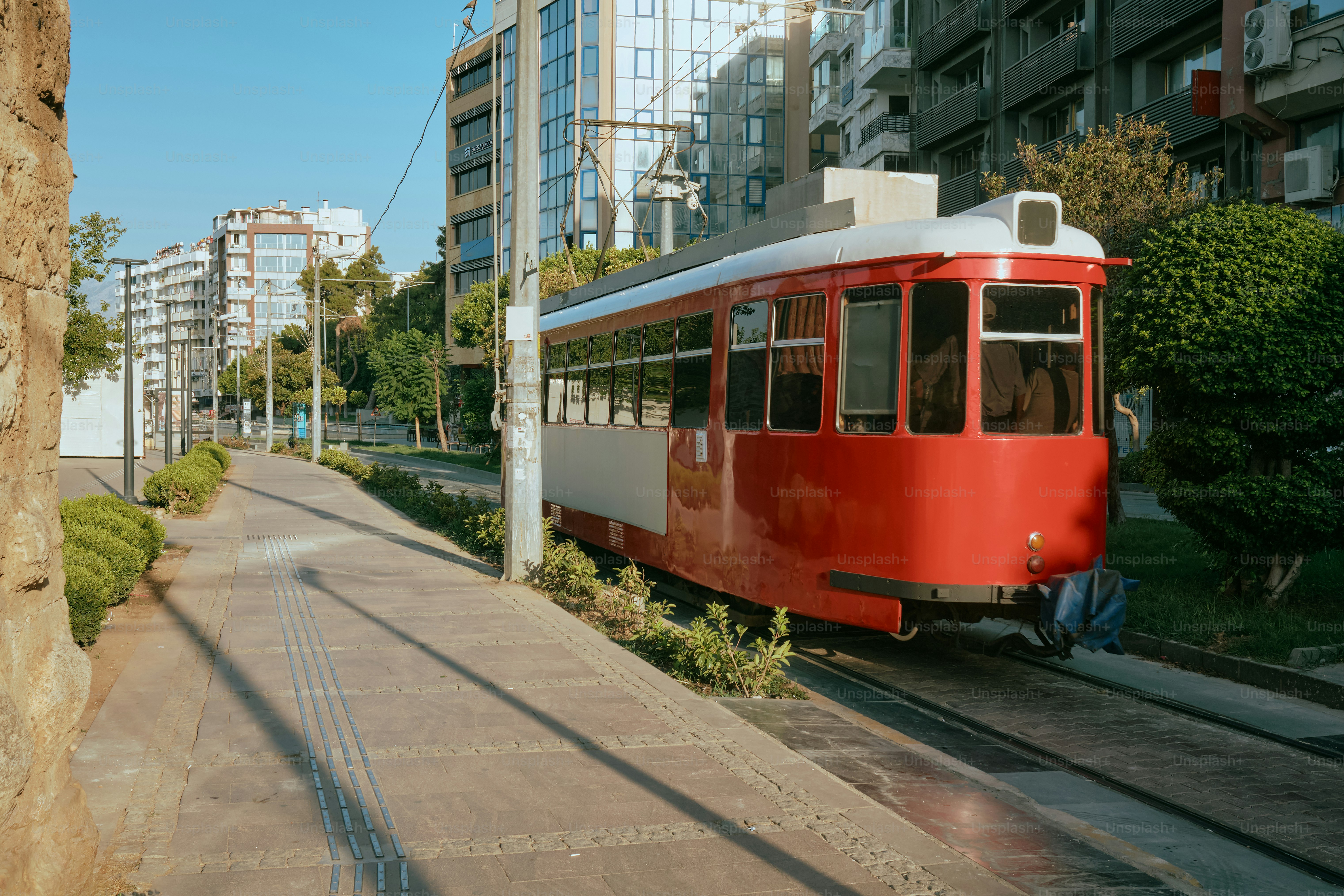 A red tram car on tracks in an urban setting.