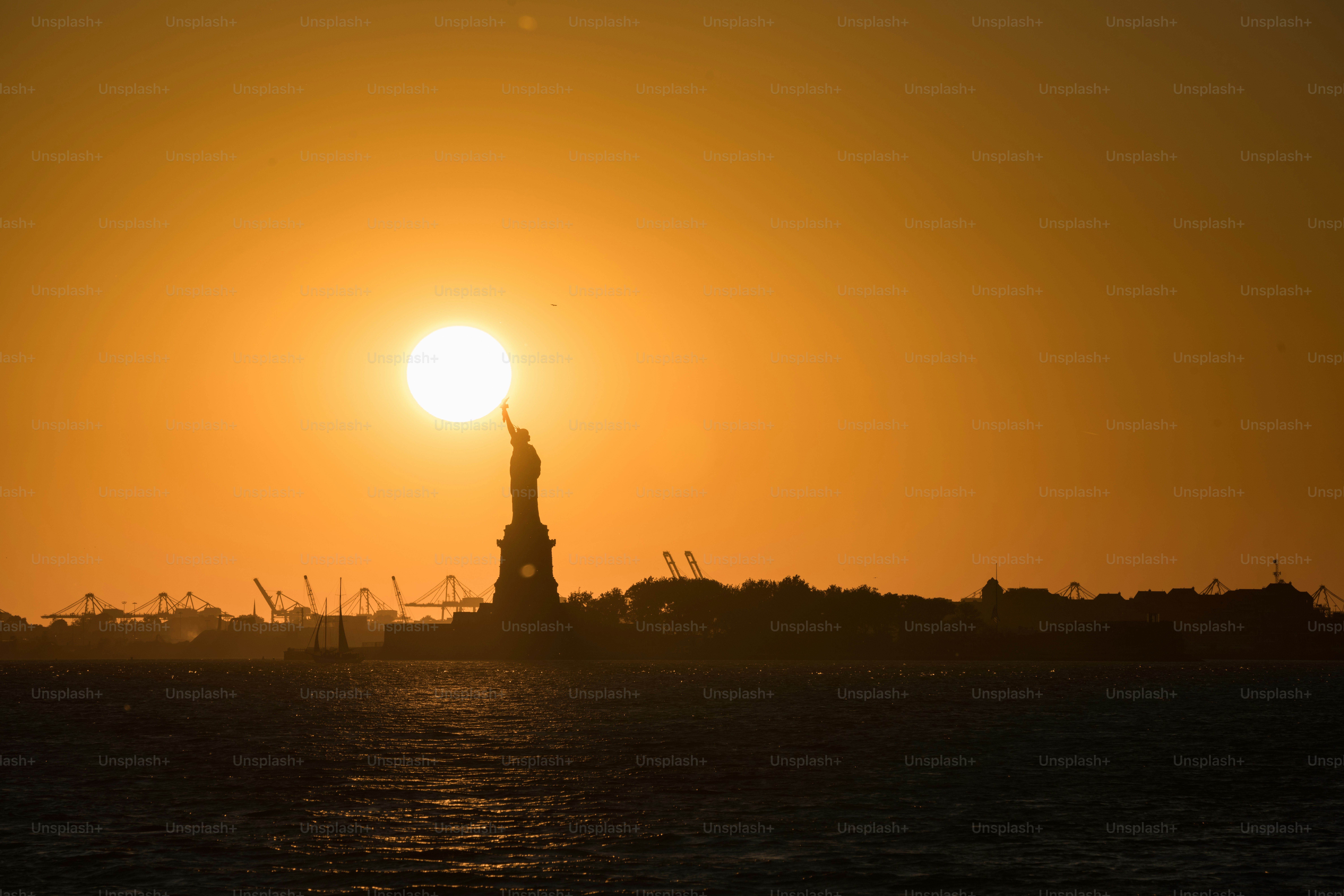 Statue of liberty silhouetted at sunset.