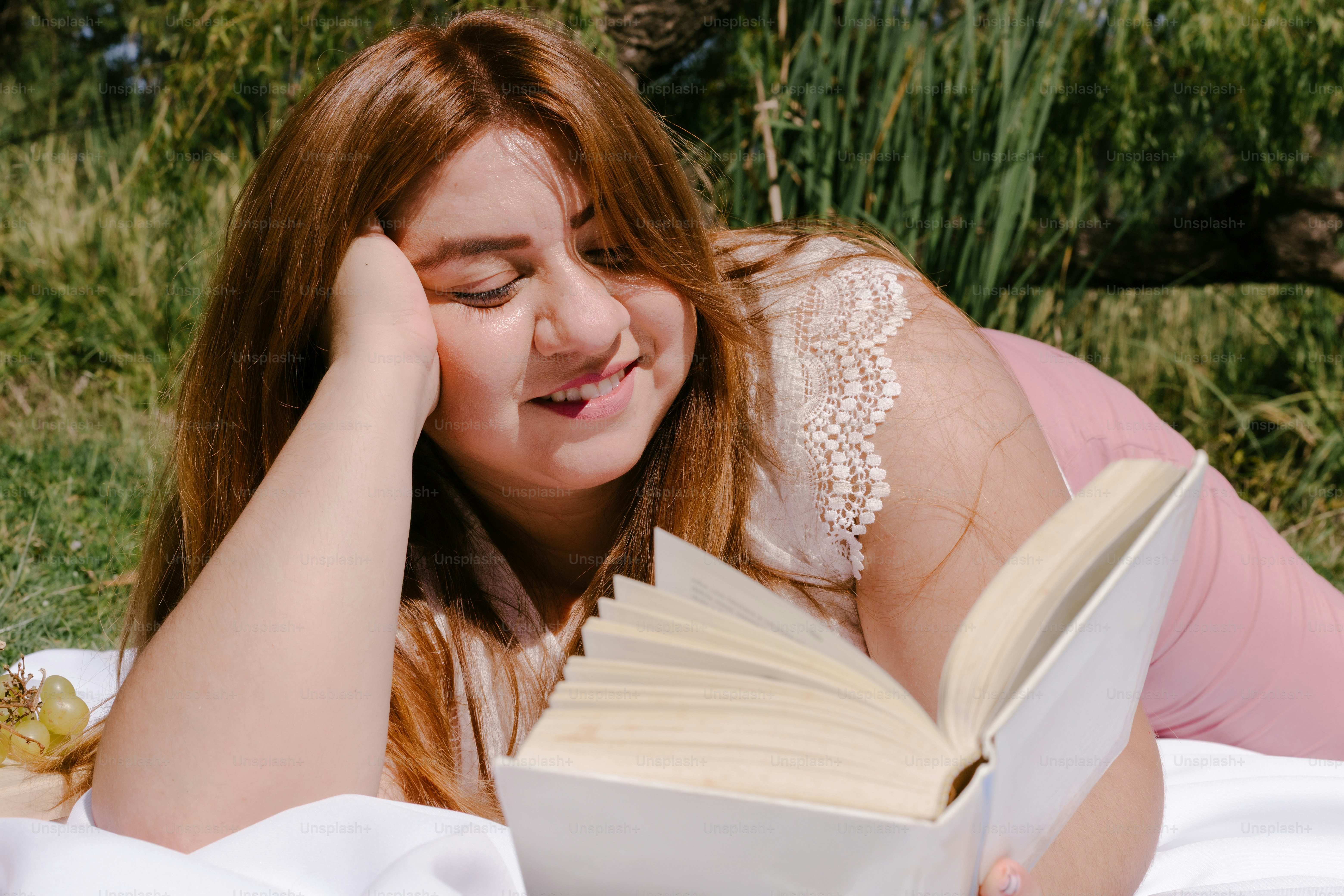 A woman happily reads a book outdoors.
