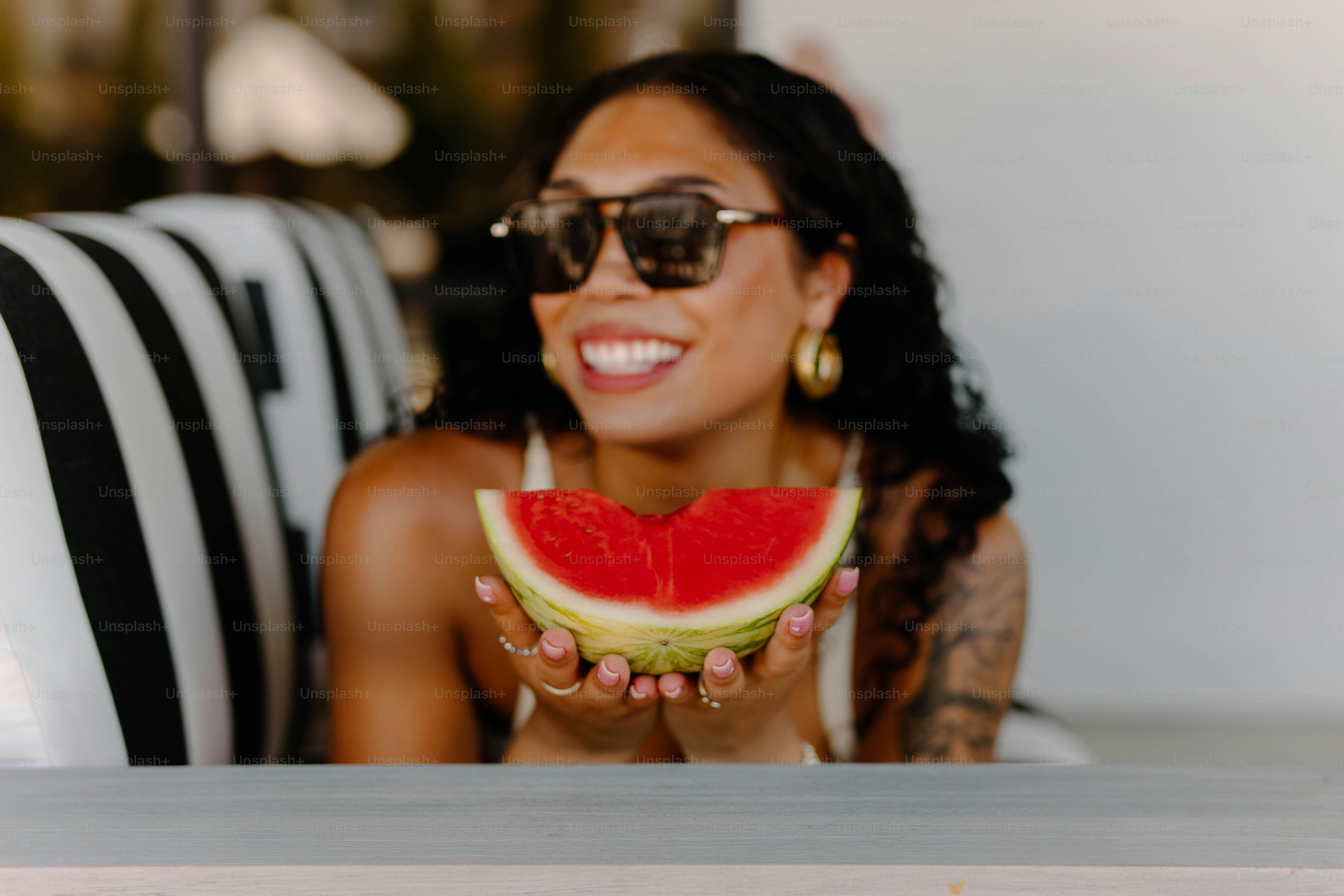 Woman enjoys watermelon and smiles cheerfully.