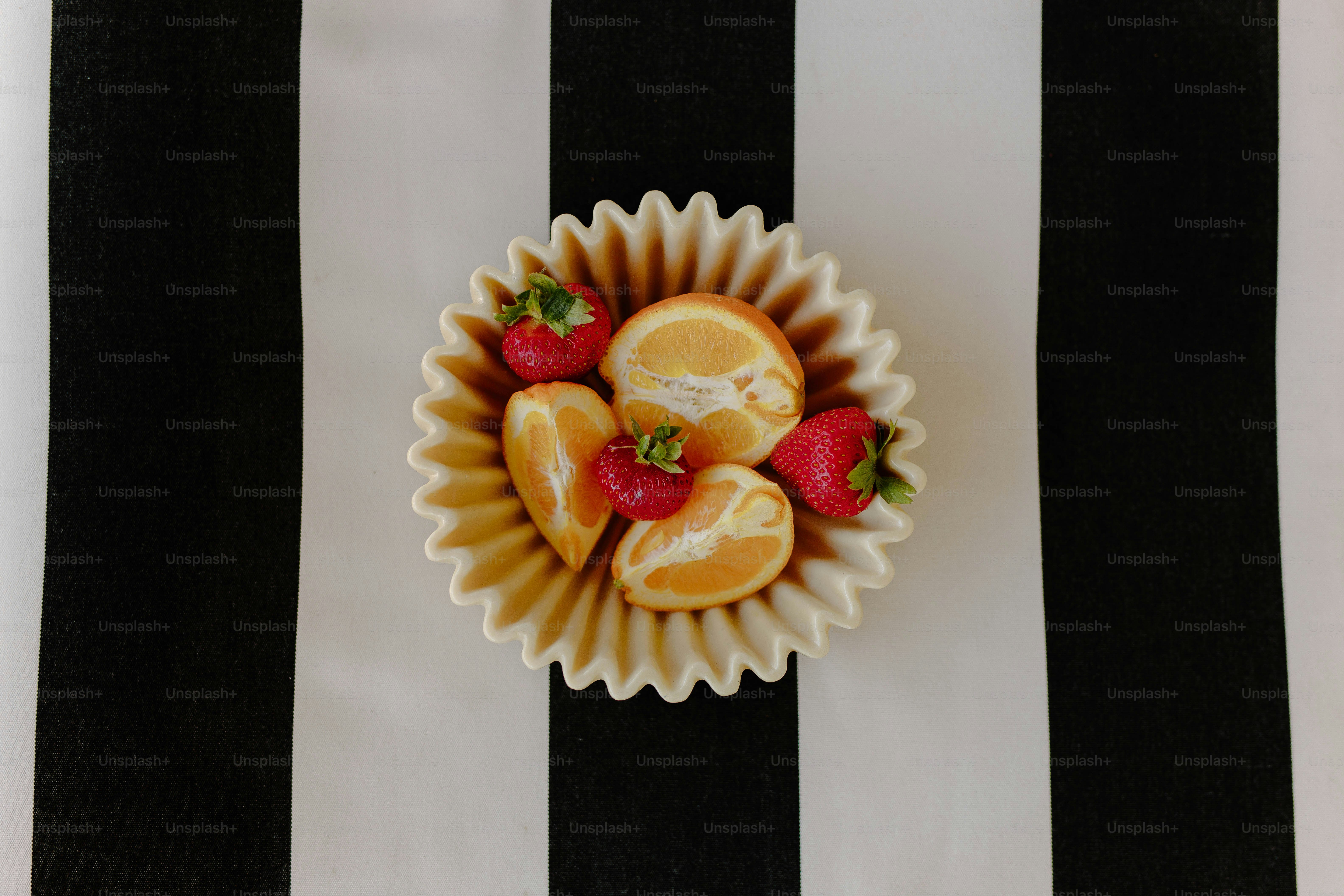Oranges and strawberries sit in a cupcake liner.