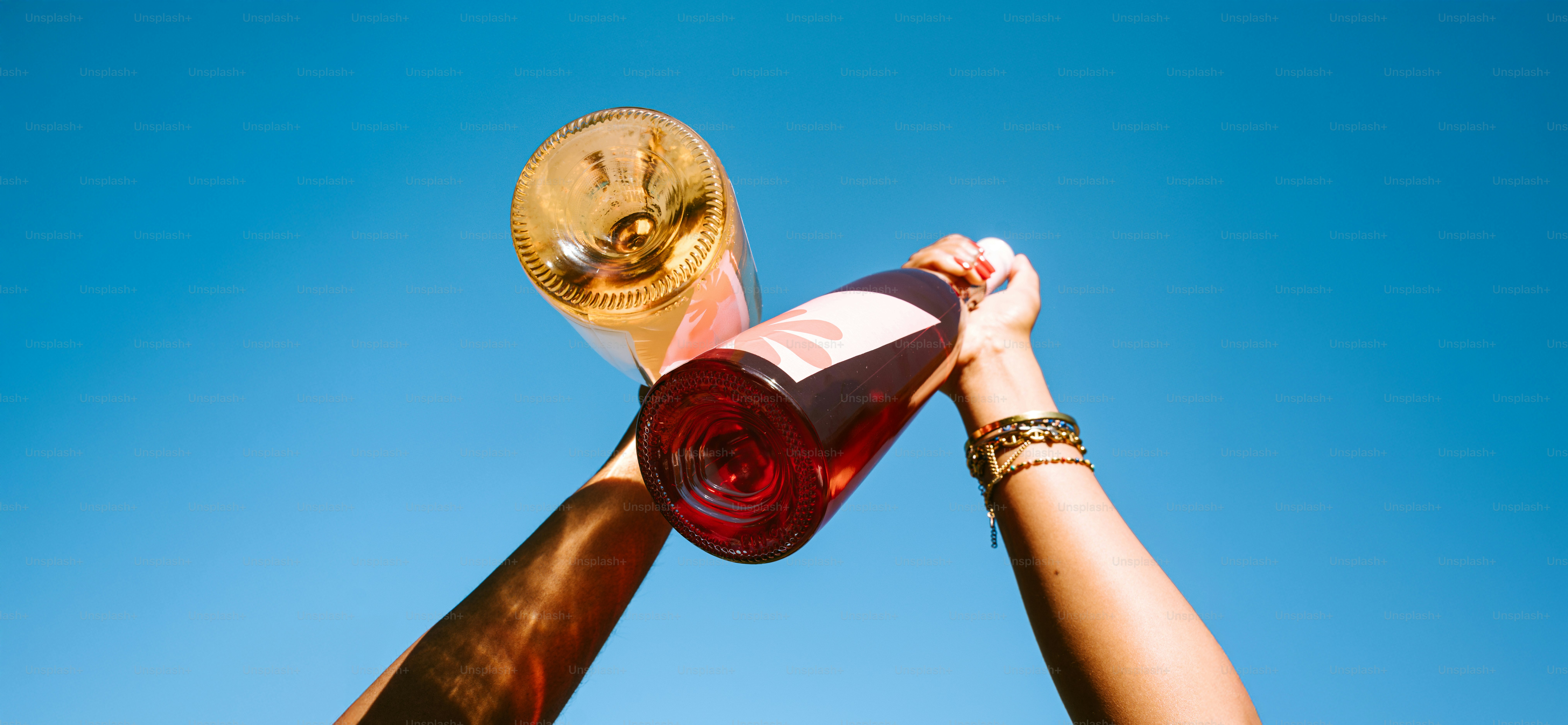 Quelqu’un tient du vin et un verre vers le ciel.