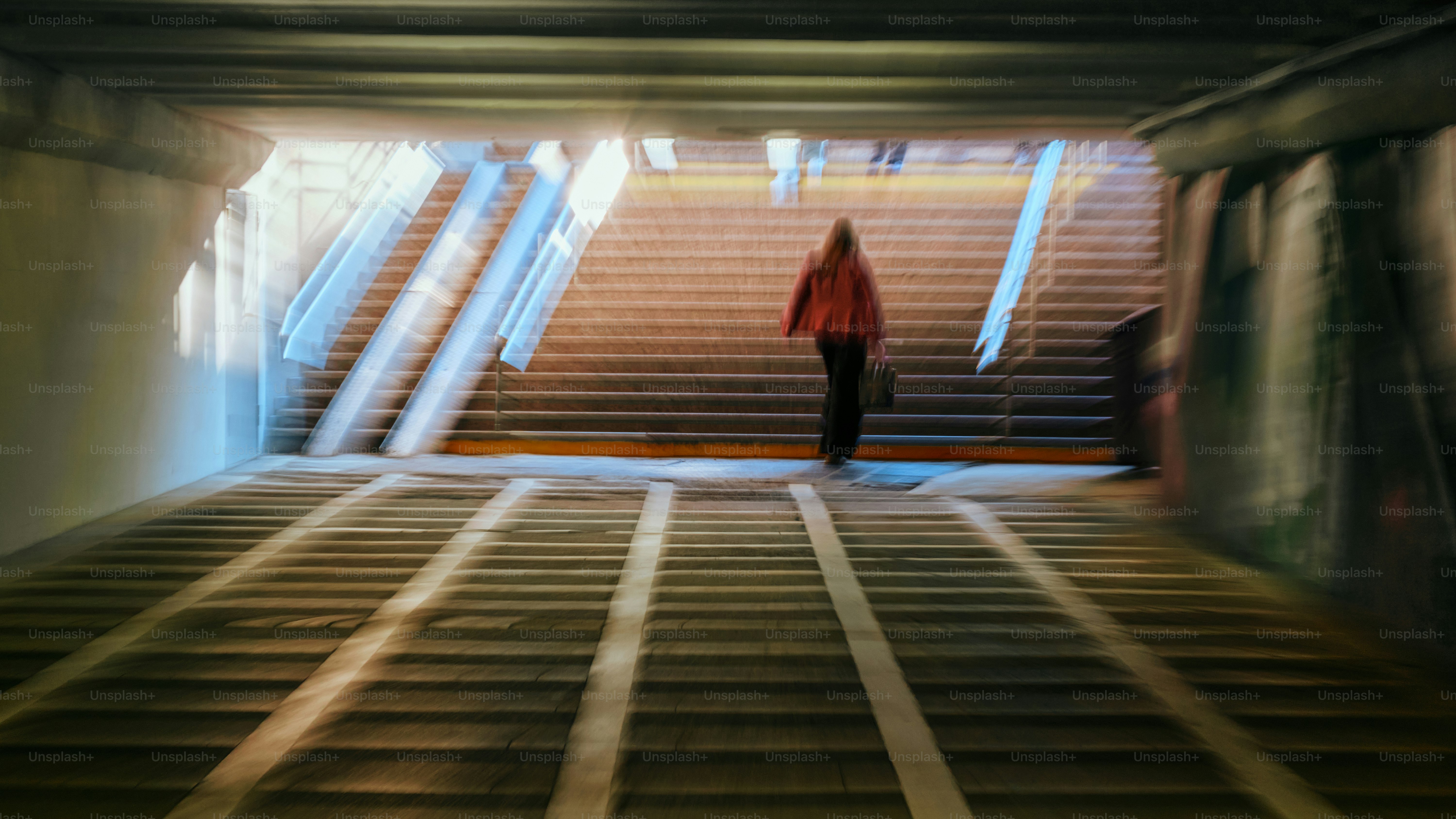 A person walks up stairs towards the light.