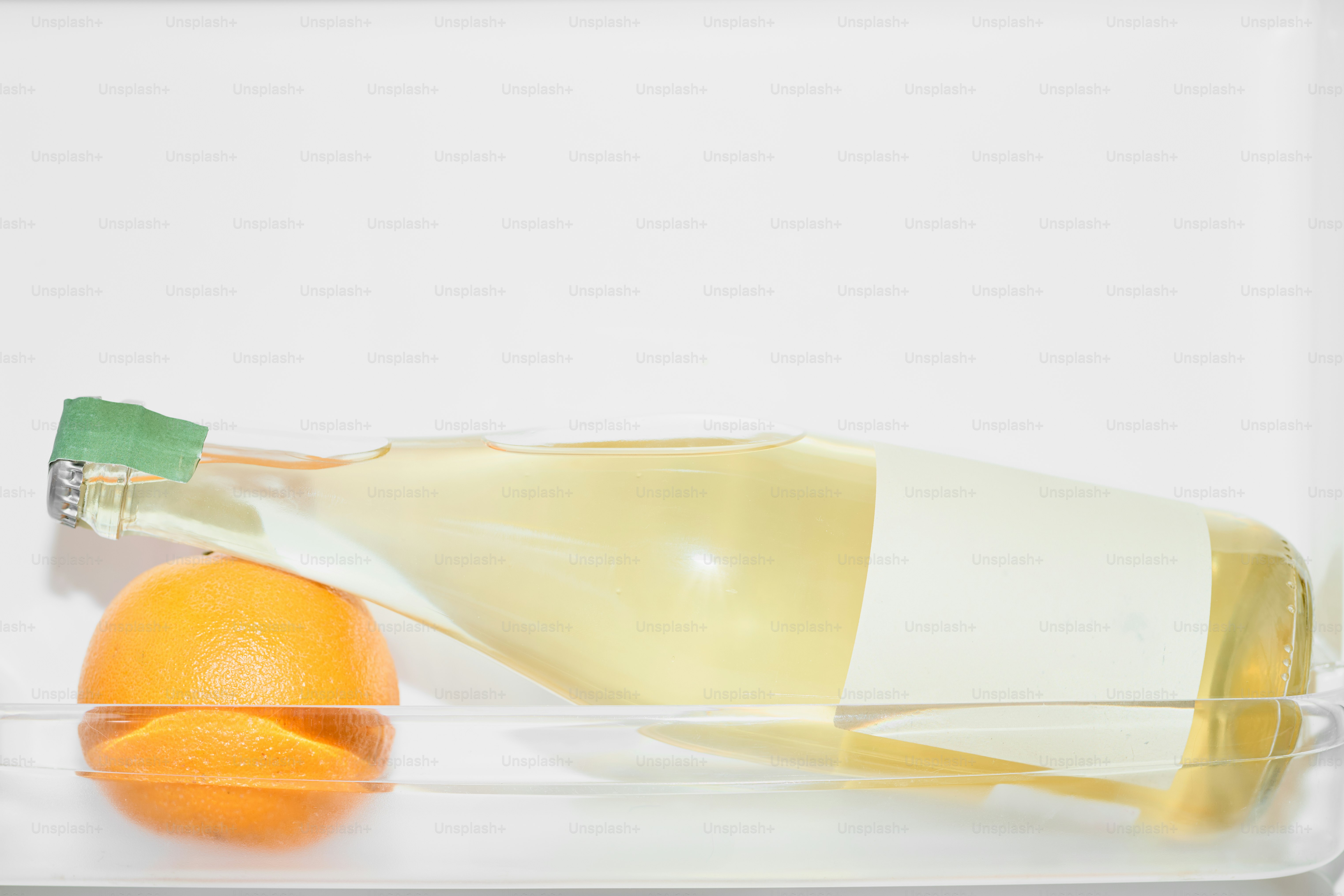 A bottle of wine and an orange in the fridge.