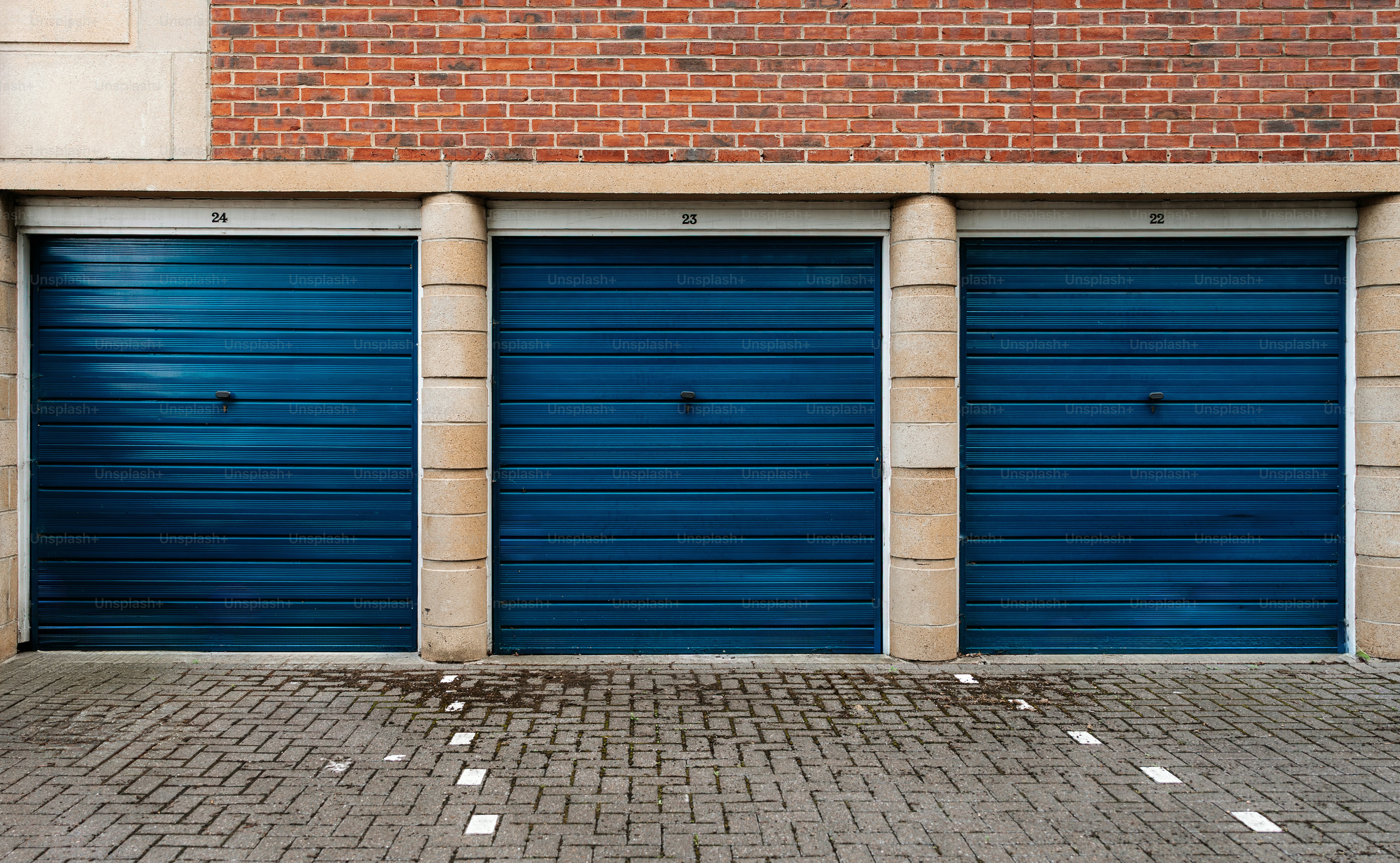 Drei blaue Garagentore gegen Backsteine.