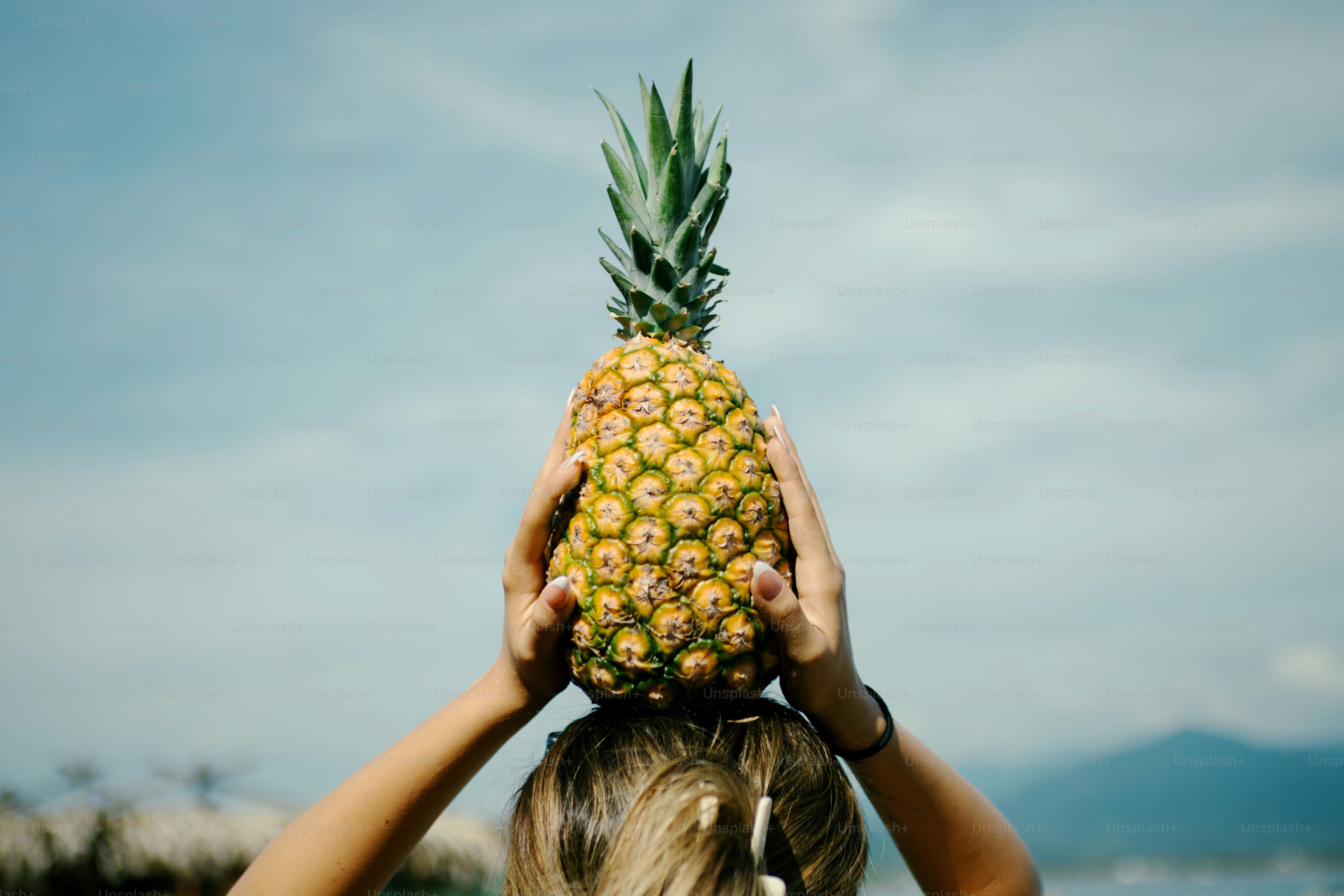 Quelqu’un tient un ananas au-dessus de sa tête.