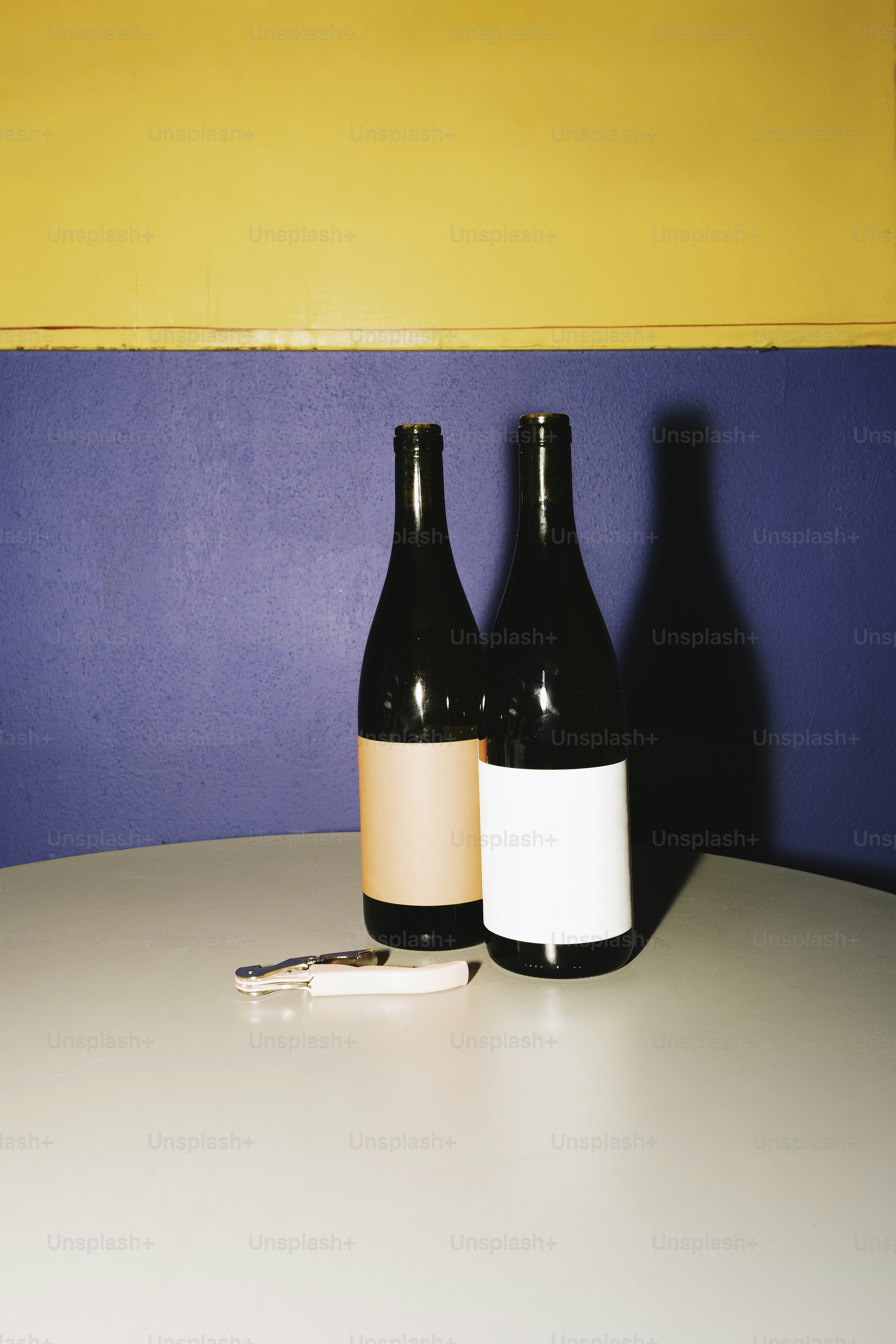 Two wine bottles sit on a table.