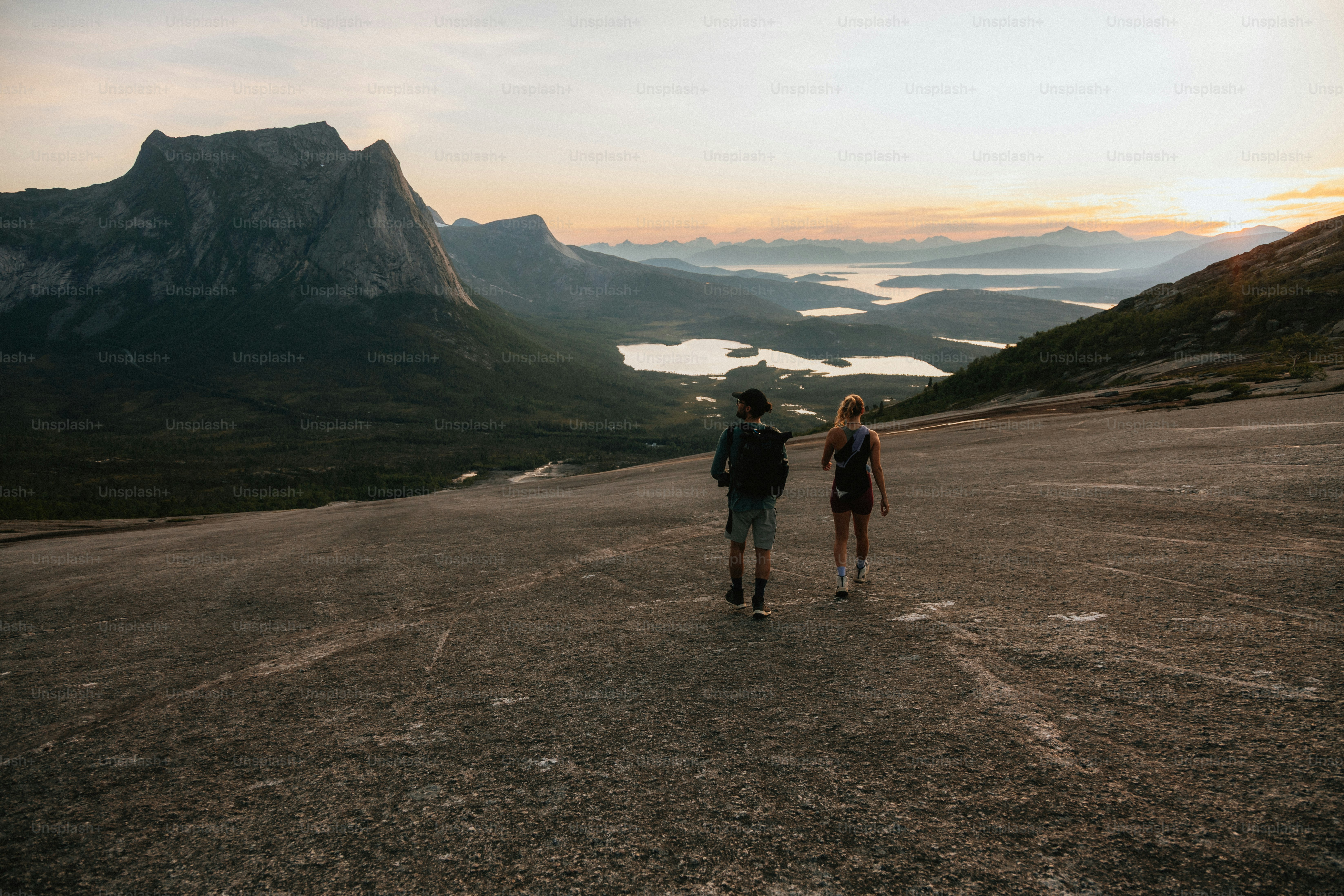 Two hikers enjoy the mountain views at sunset.