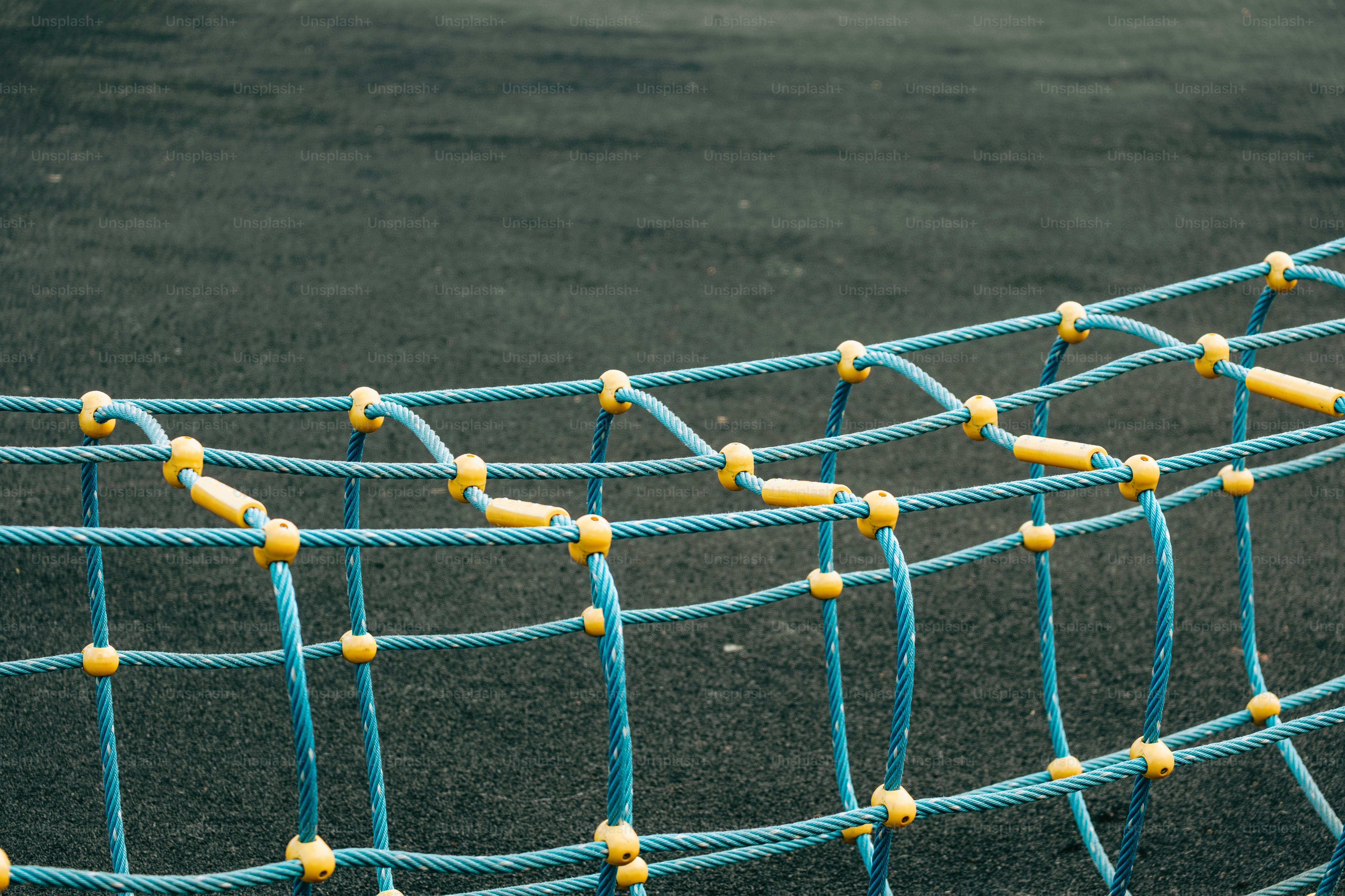Blue and yellow netting on a playground surface.