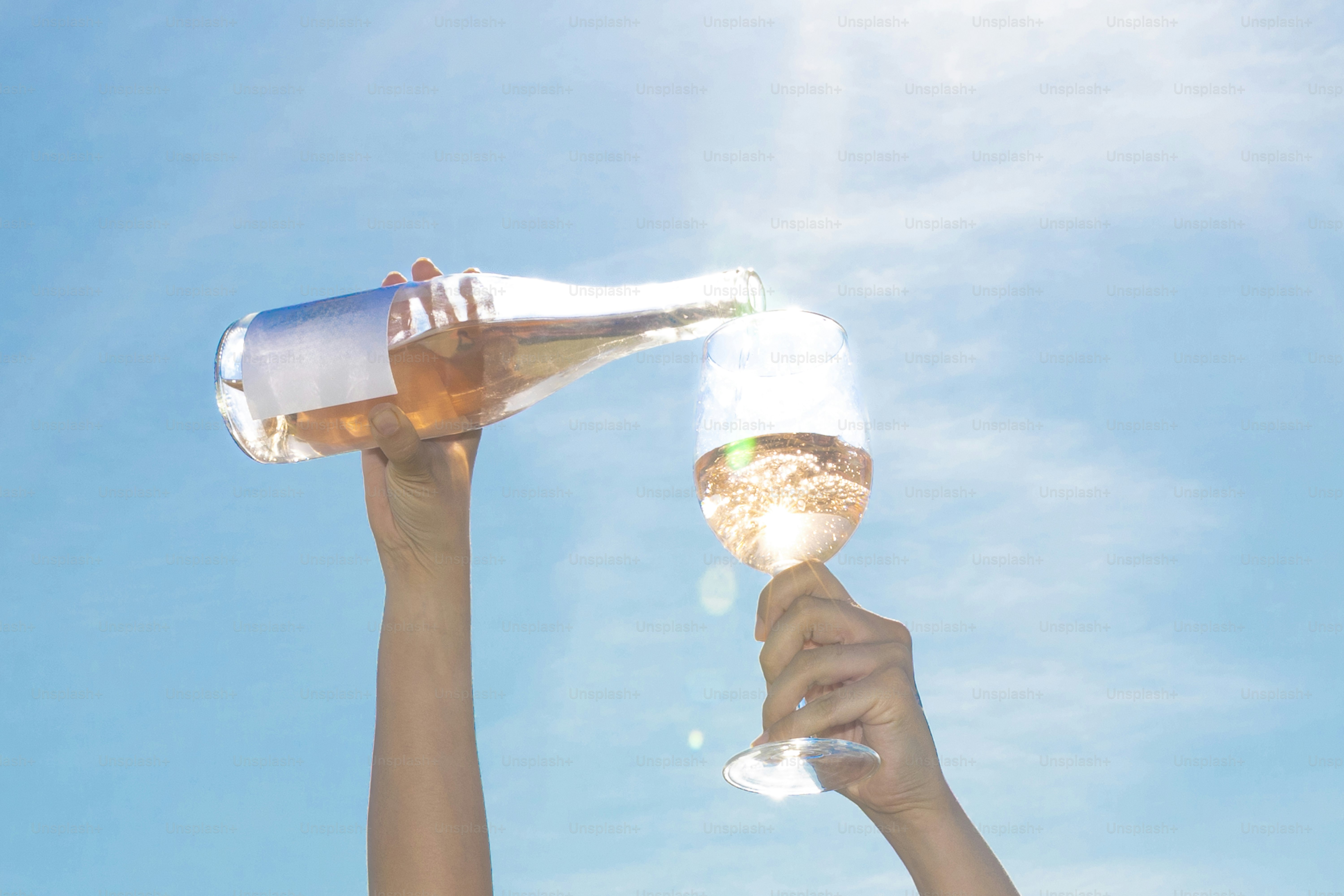 Wine is poured into a glass under the bright sky