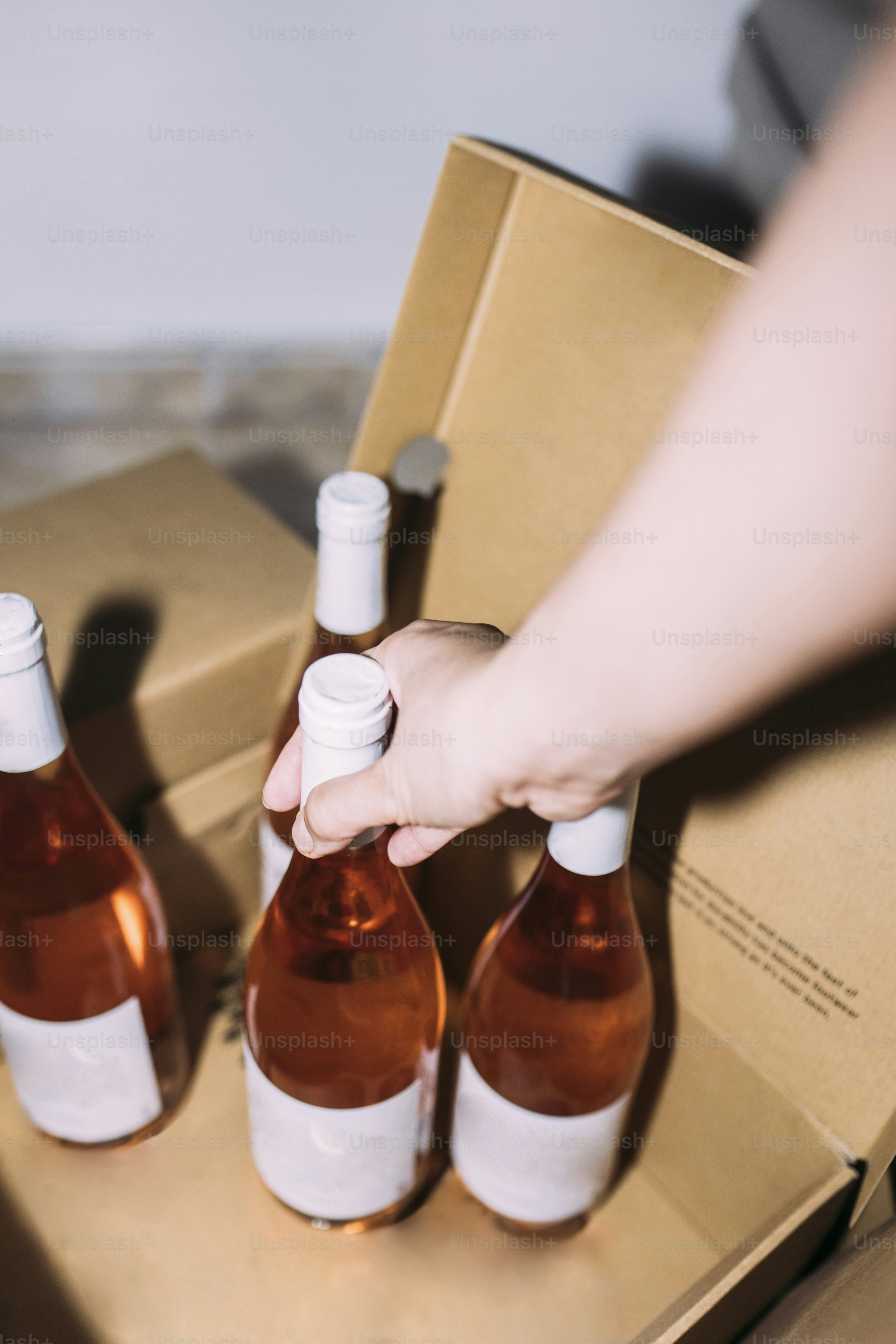 Winemaker taking a bottle of rosé natural wine from a cardboard box in a winery cellar
