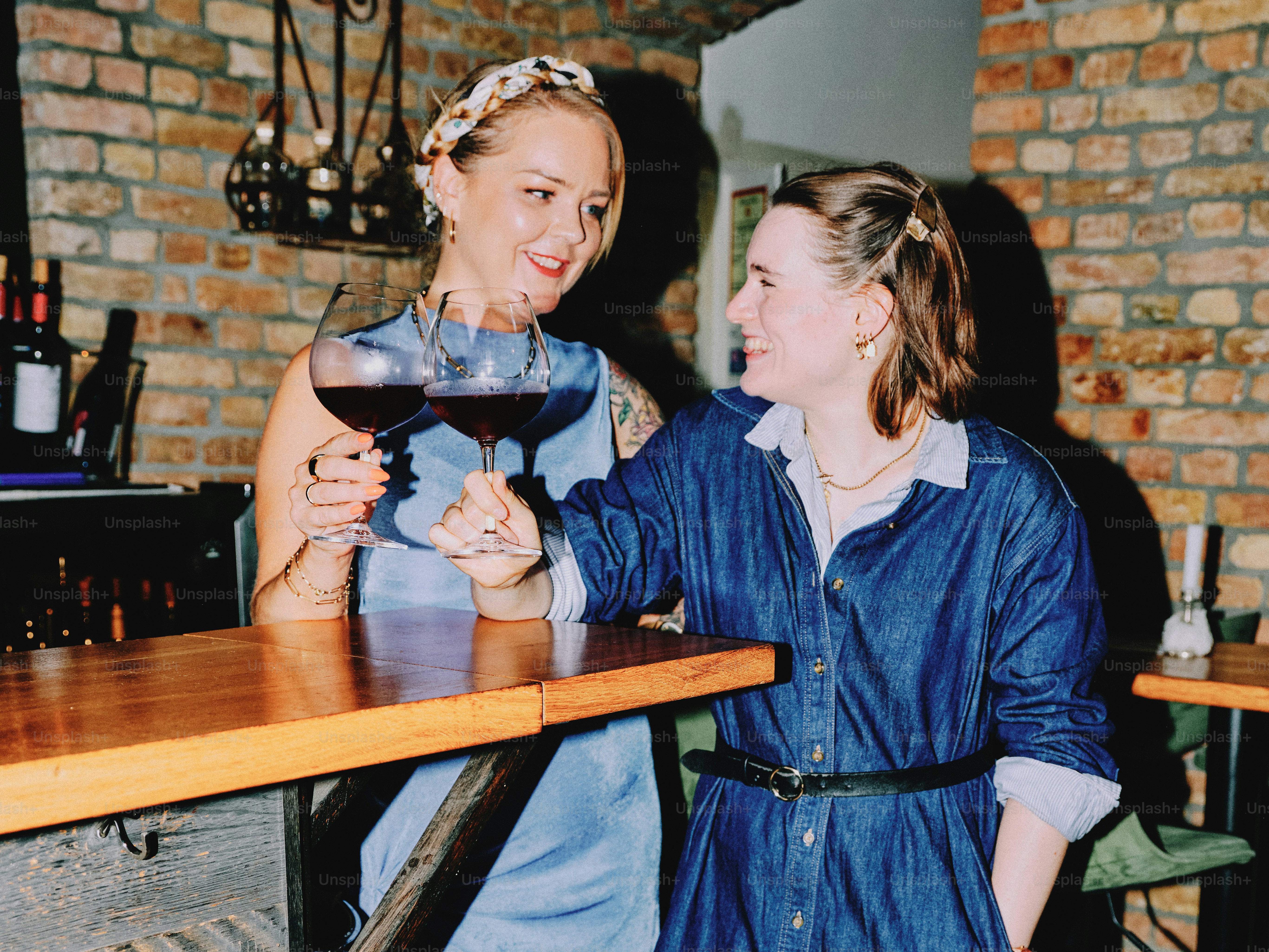 Two women enjoy wine together at a bar.