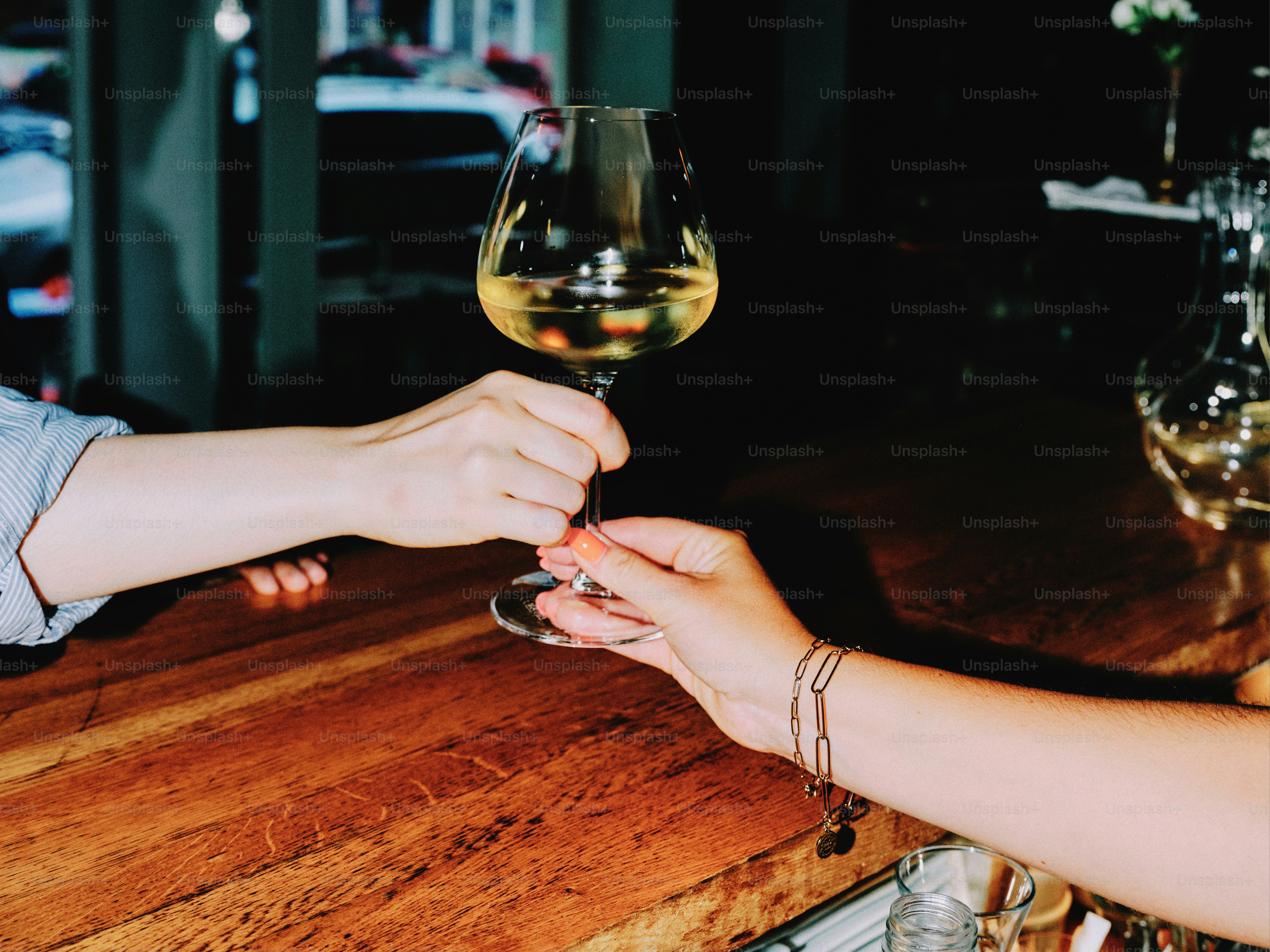 Cheers! someone is handing a glass of wine. photo  Purple Image on Unsplash
