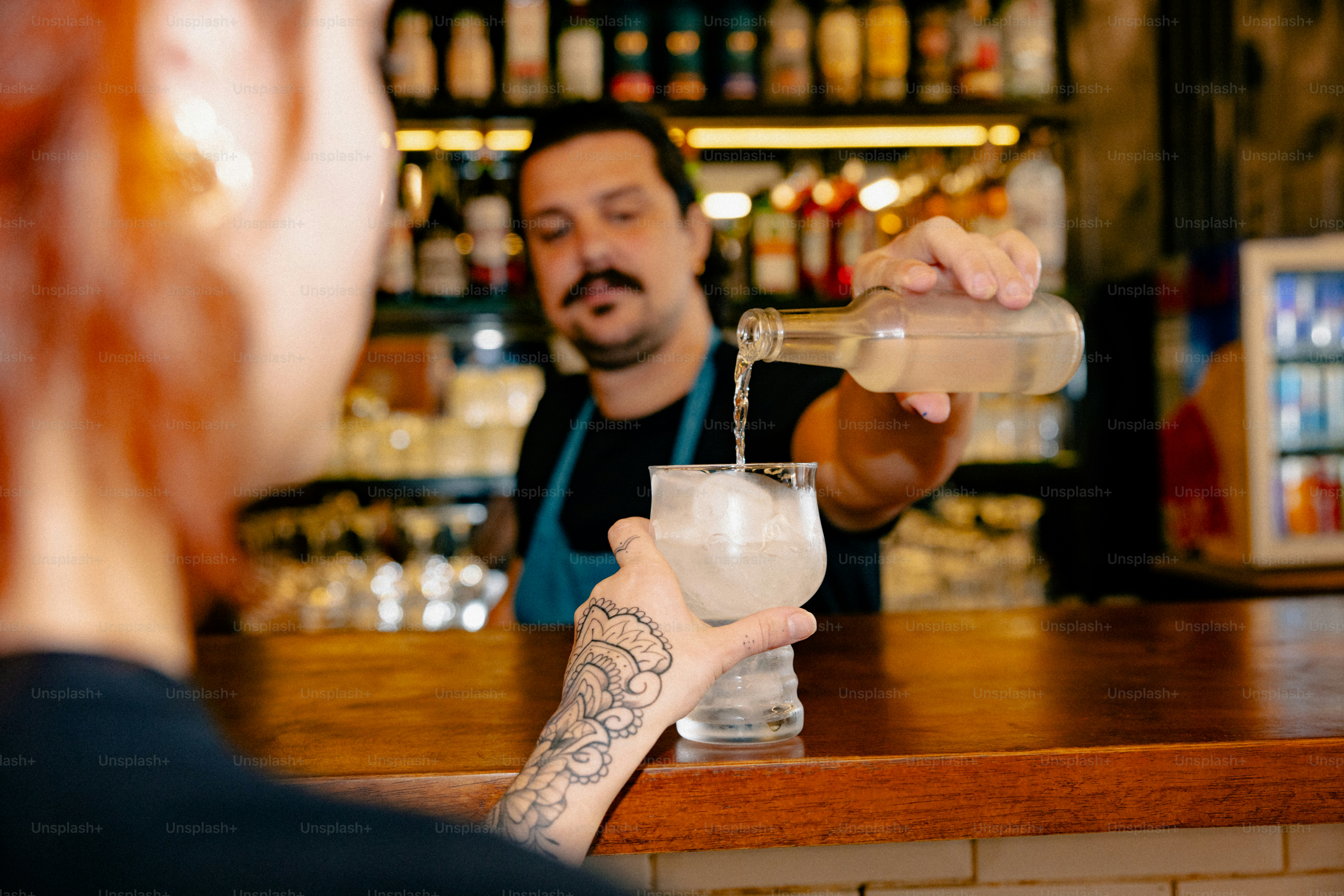 Bartender pours a drink for a customer at the bar.