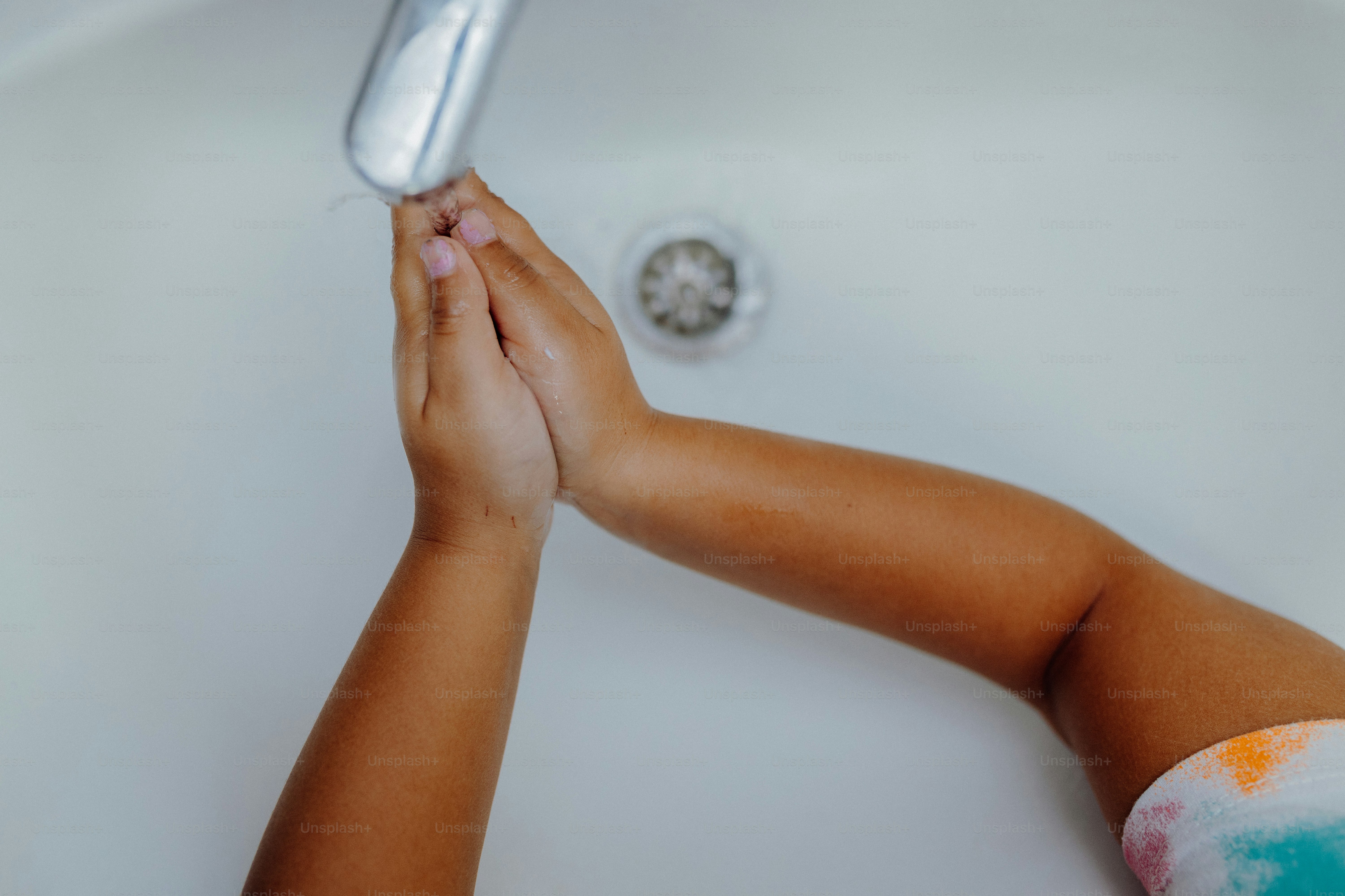A child washes their hands in the sink.