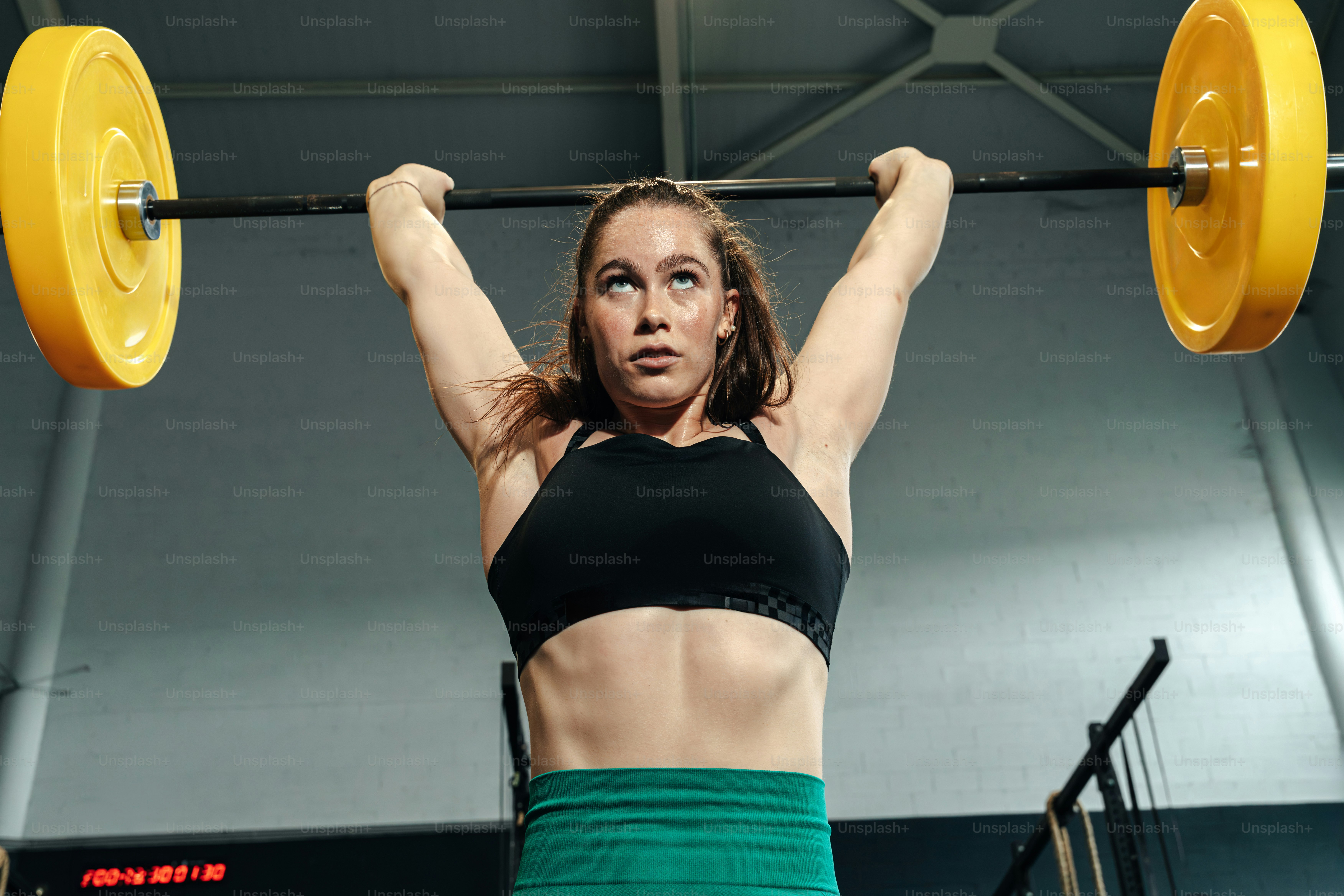 女性はトレーニング中にバーベルを頭上に持ち上げます。の写真