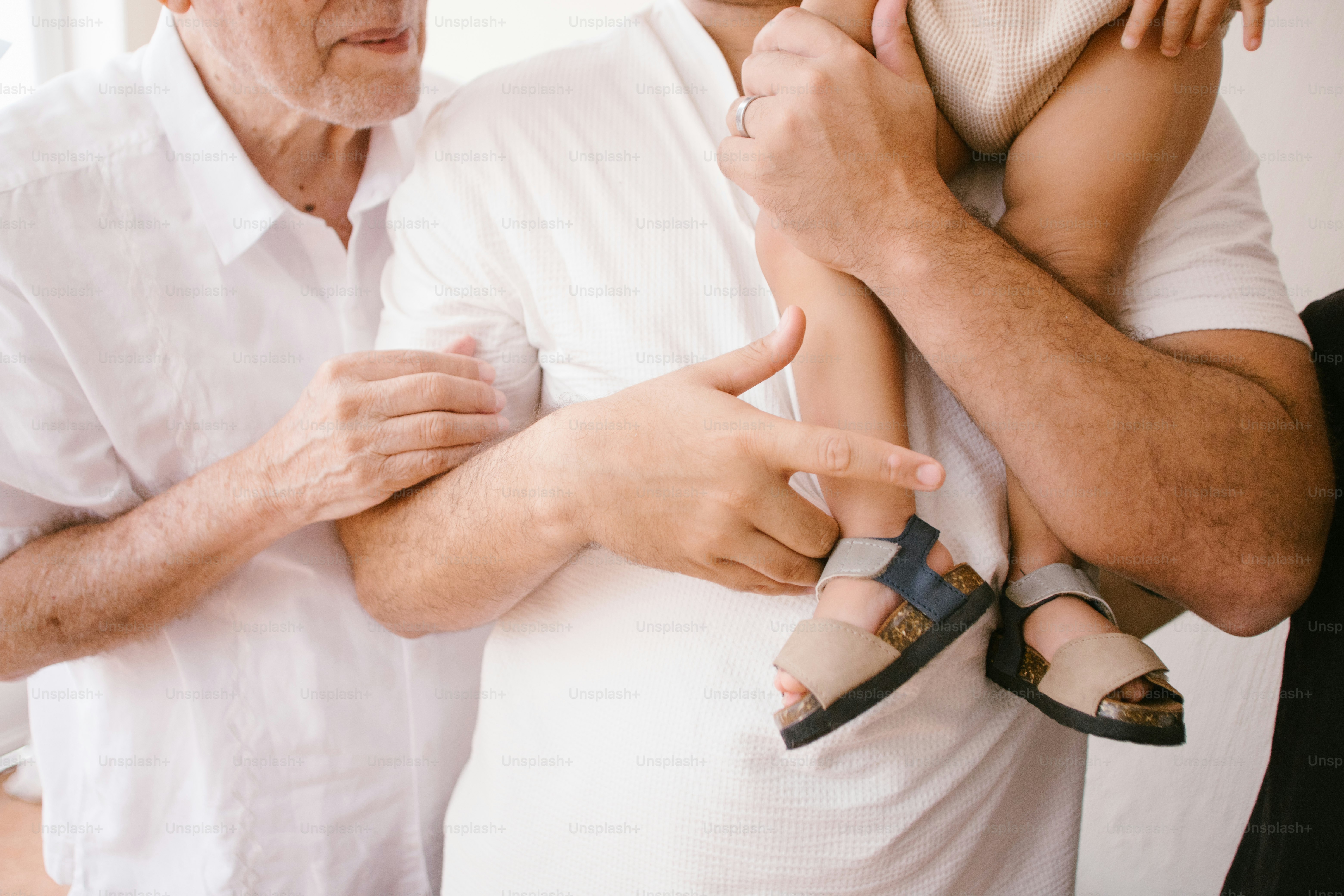 Family members are holding and supporting a young child.
