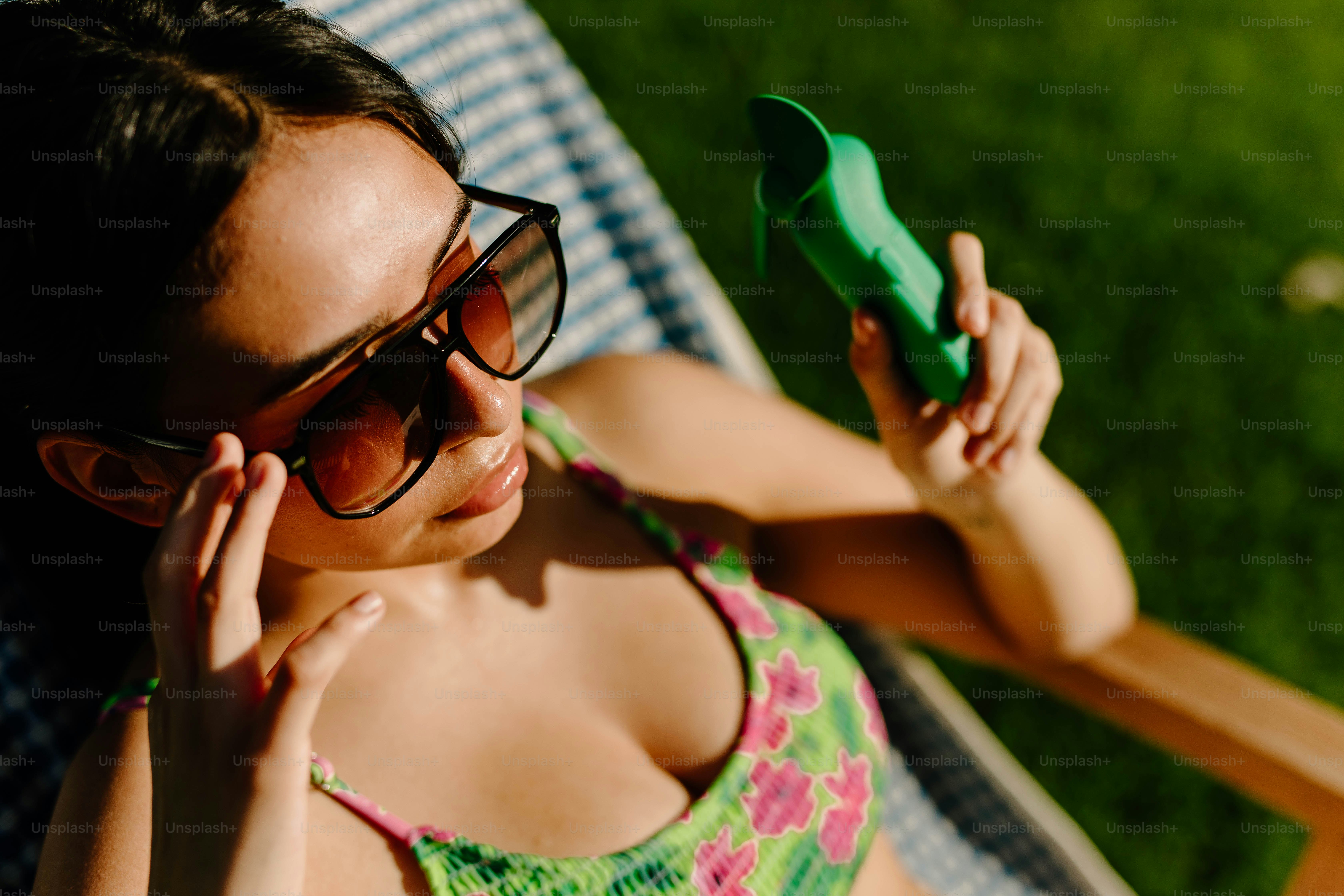 Mulher relaxa ao sol com óculos escuros e um telefone