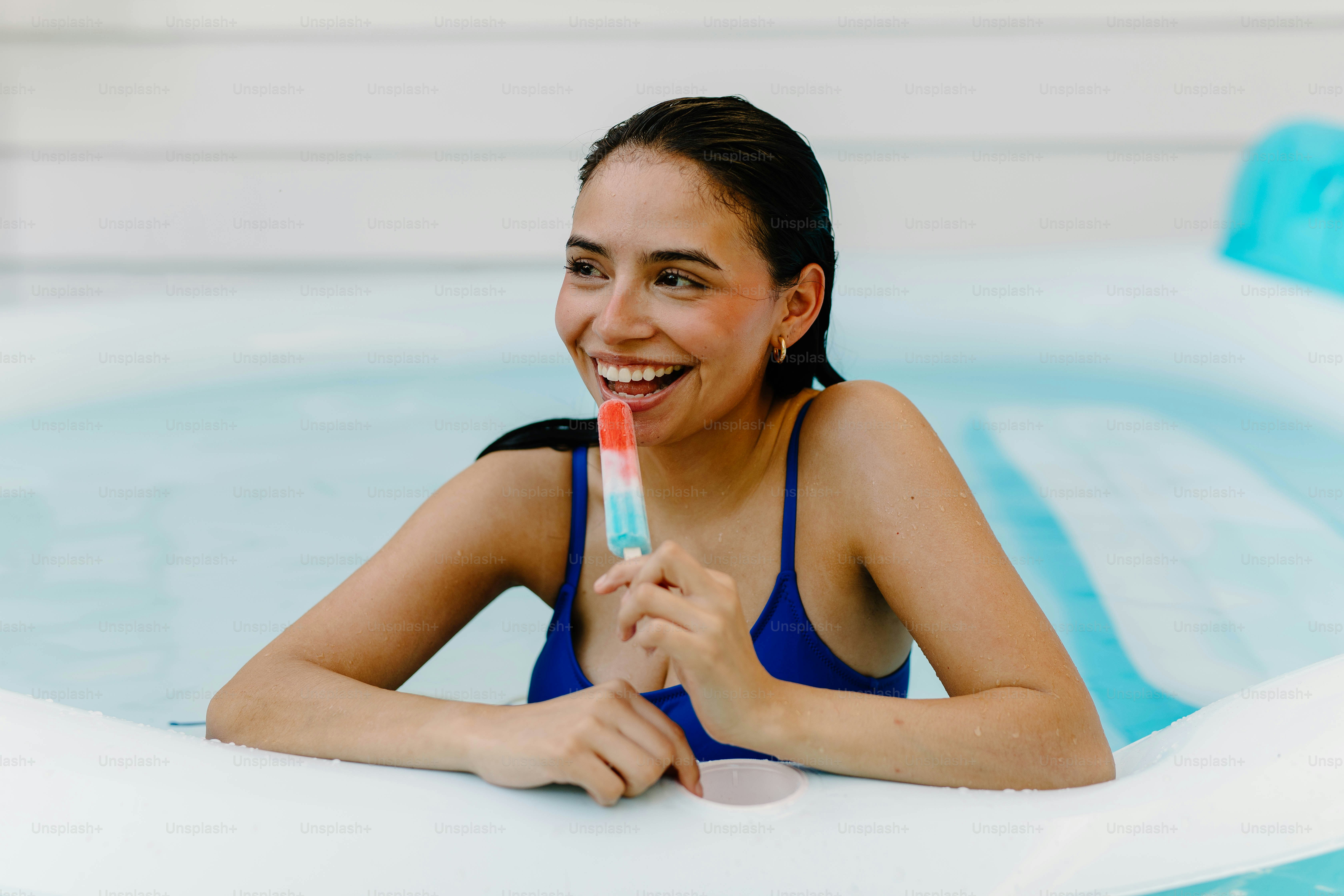 Mulher desfruta de um picolé em uma piscina
