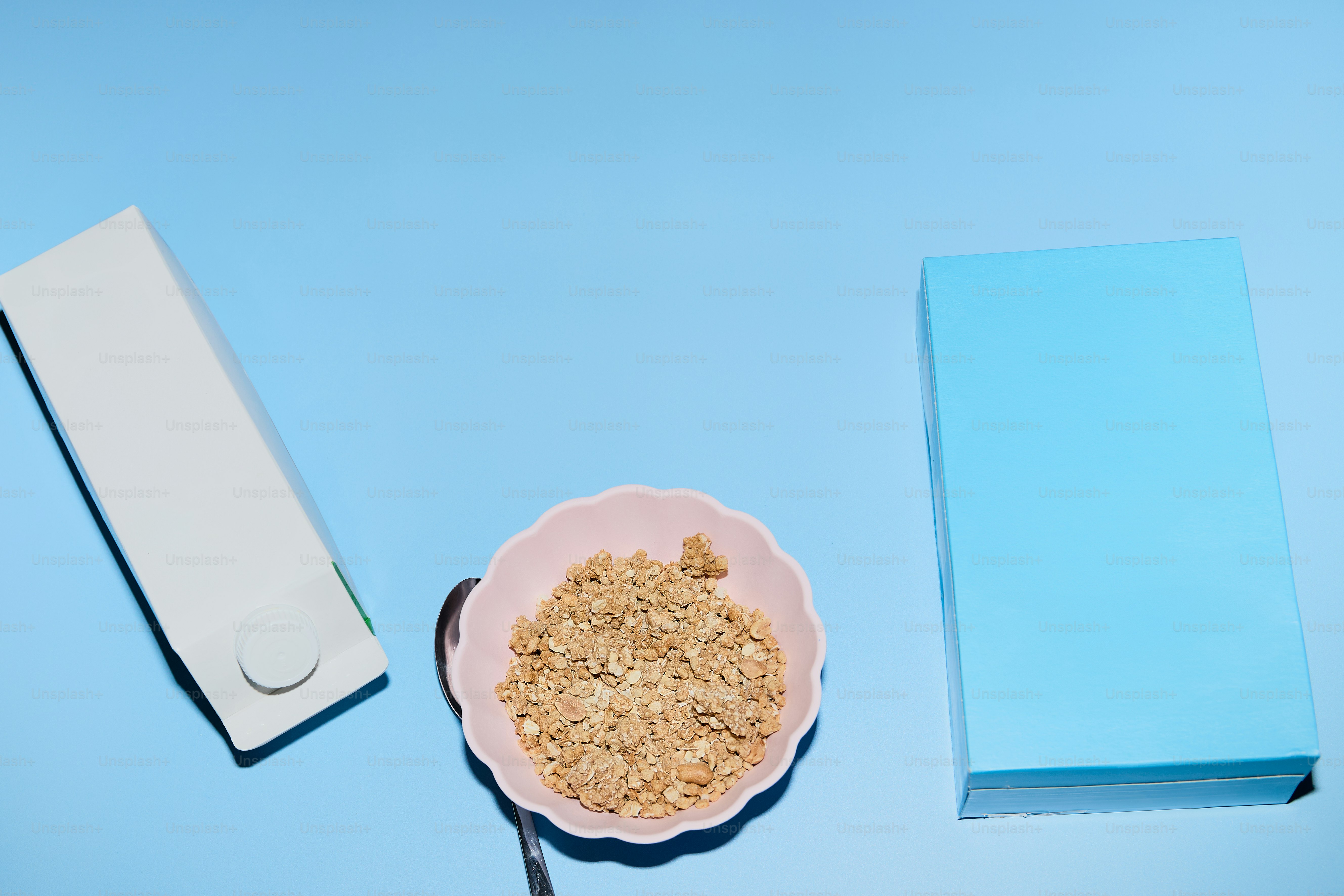 Cereal, a bowl, and a carton on a blue surface.