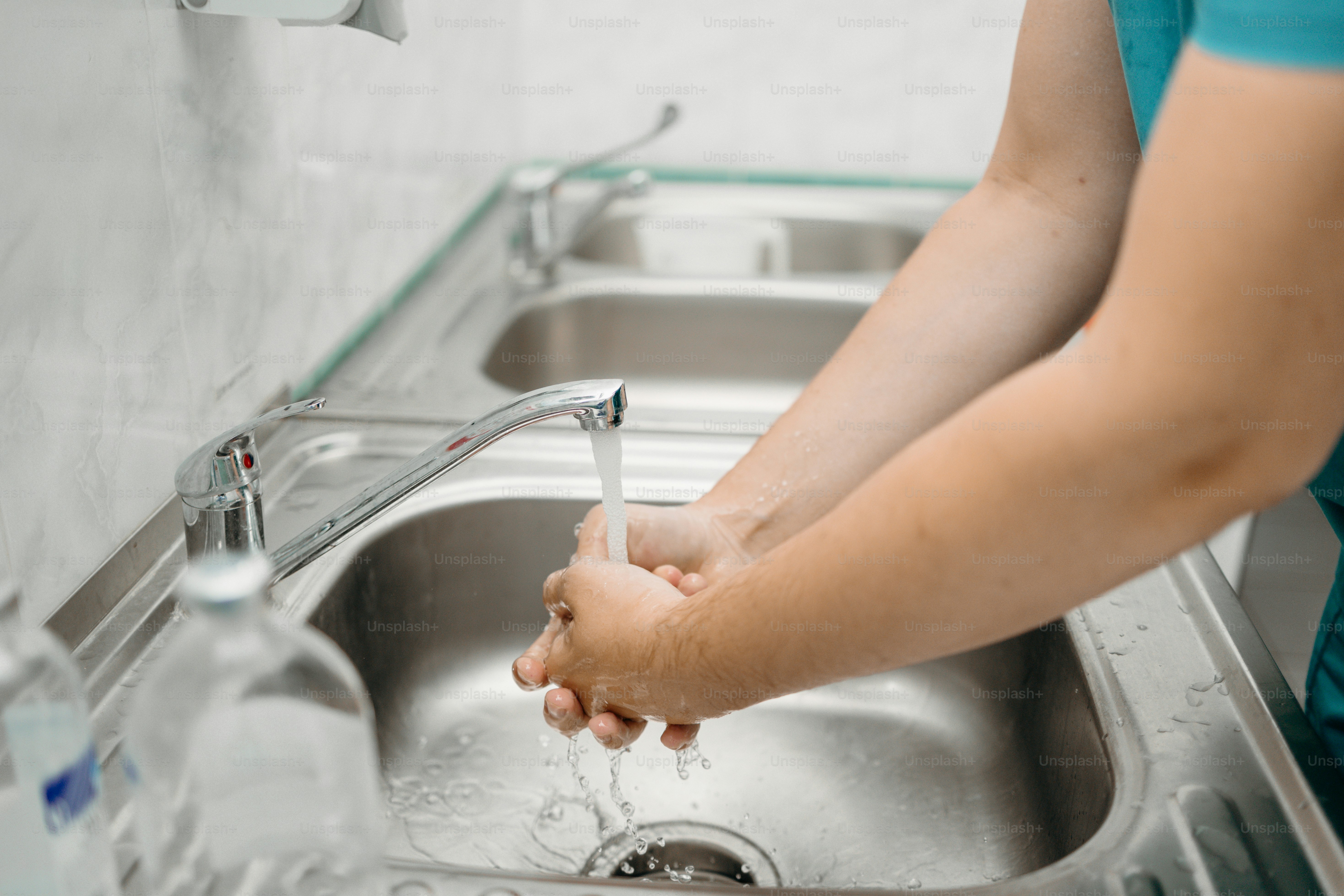 La personne se lave les mains à un évier en acier inoxydable.
