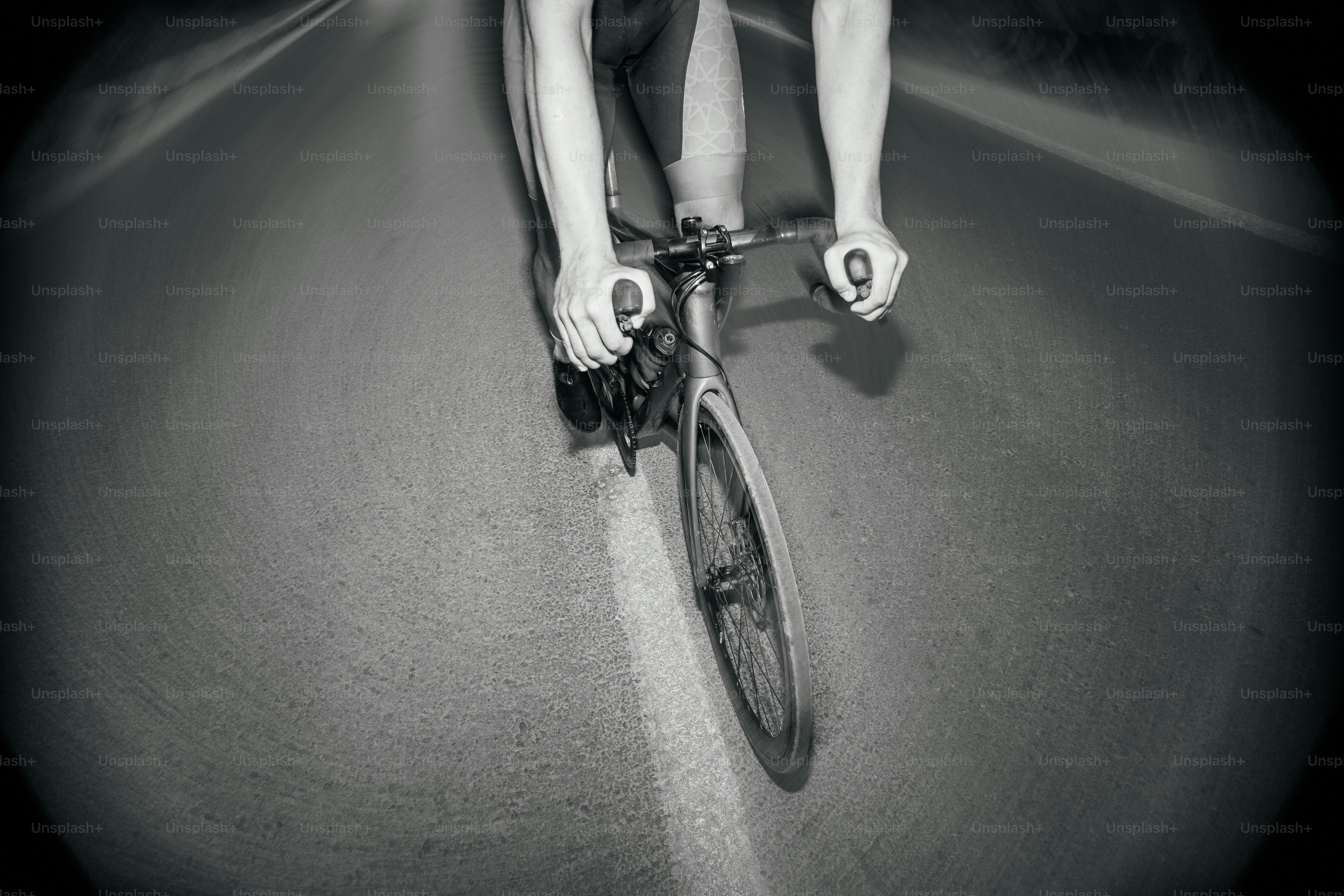 Cyclist riding quickly on a smooth, dark road.