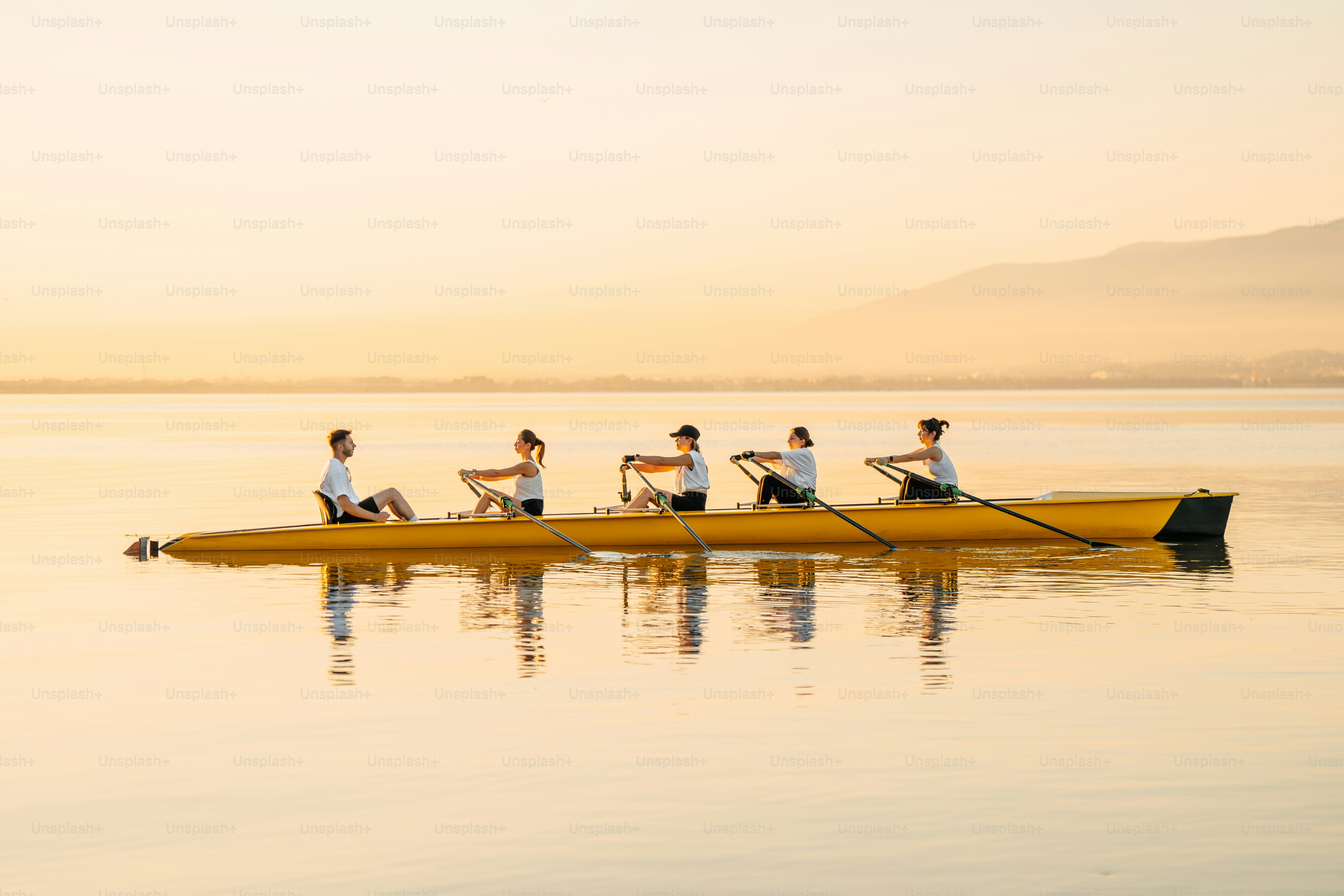Rowers propel their boat on a calm body of water