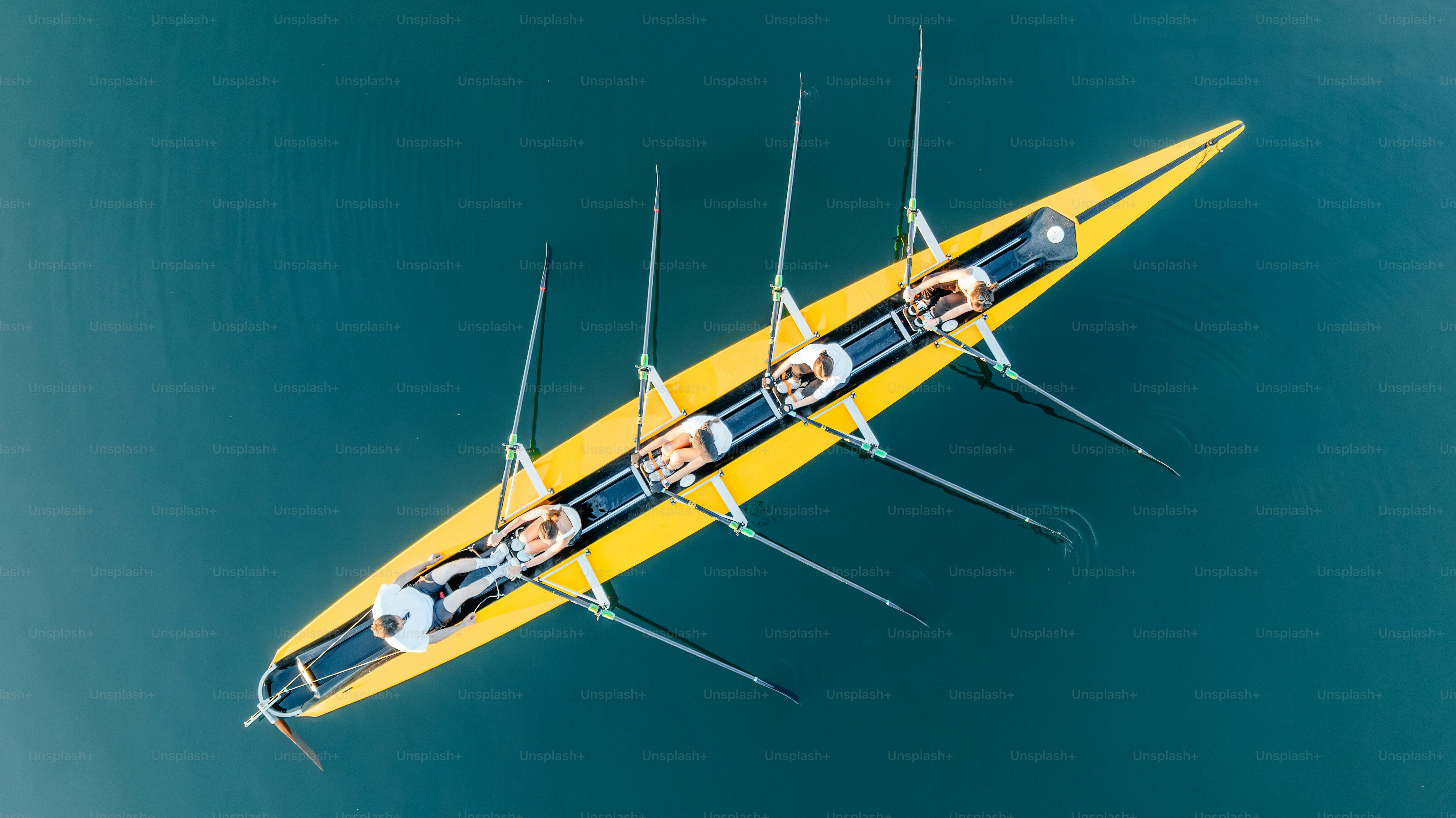 A crew team rows across calm waters. photo – Sunset Image on Unsplash