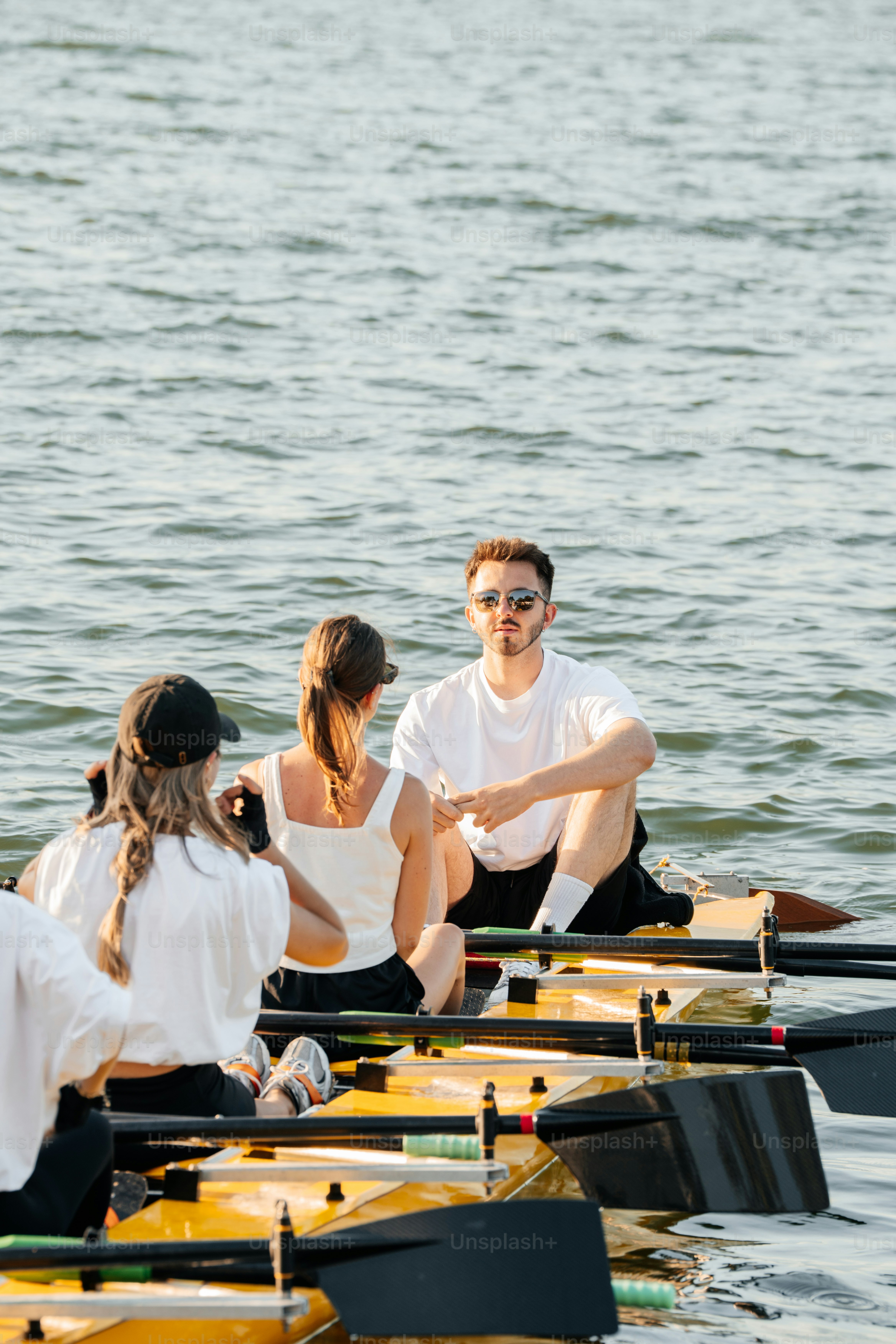 A rowing team competes on calm, blue waters. photo – Team Image on Unsplash