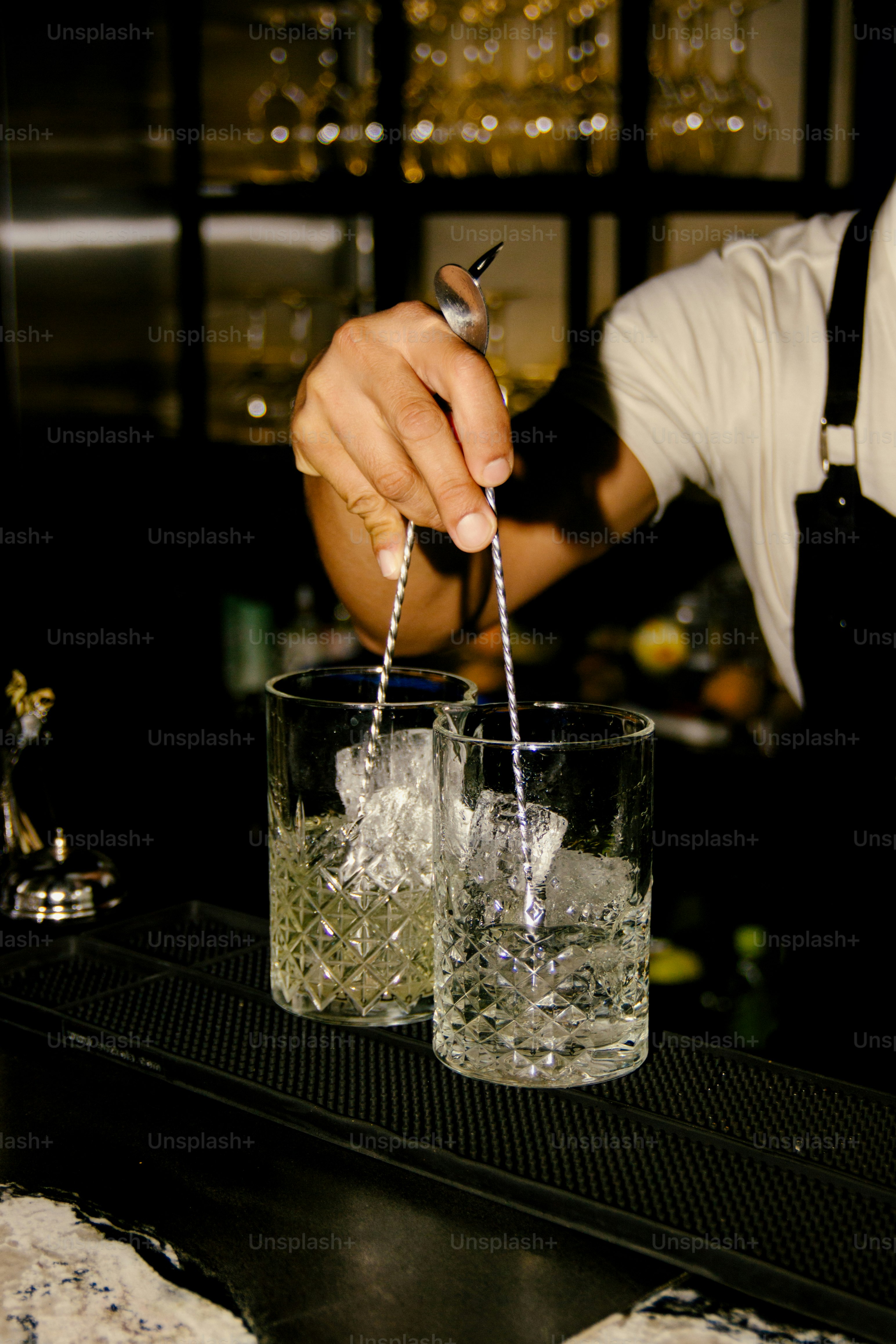 A bartender is stirring drinks behind the bar.