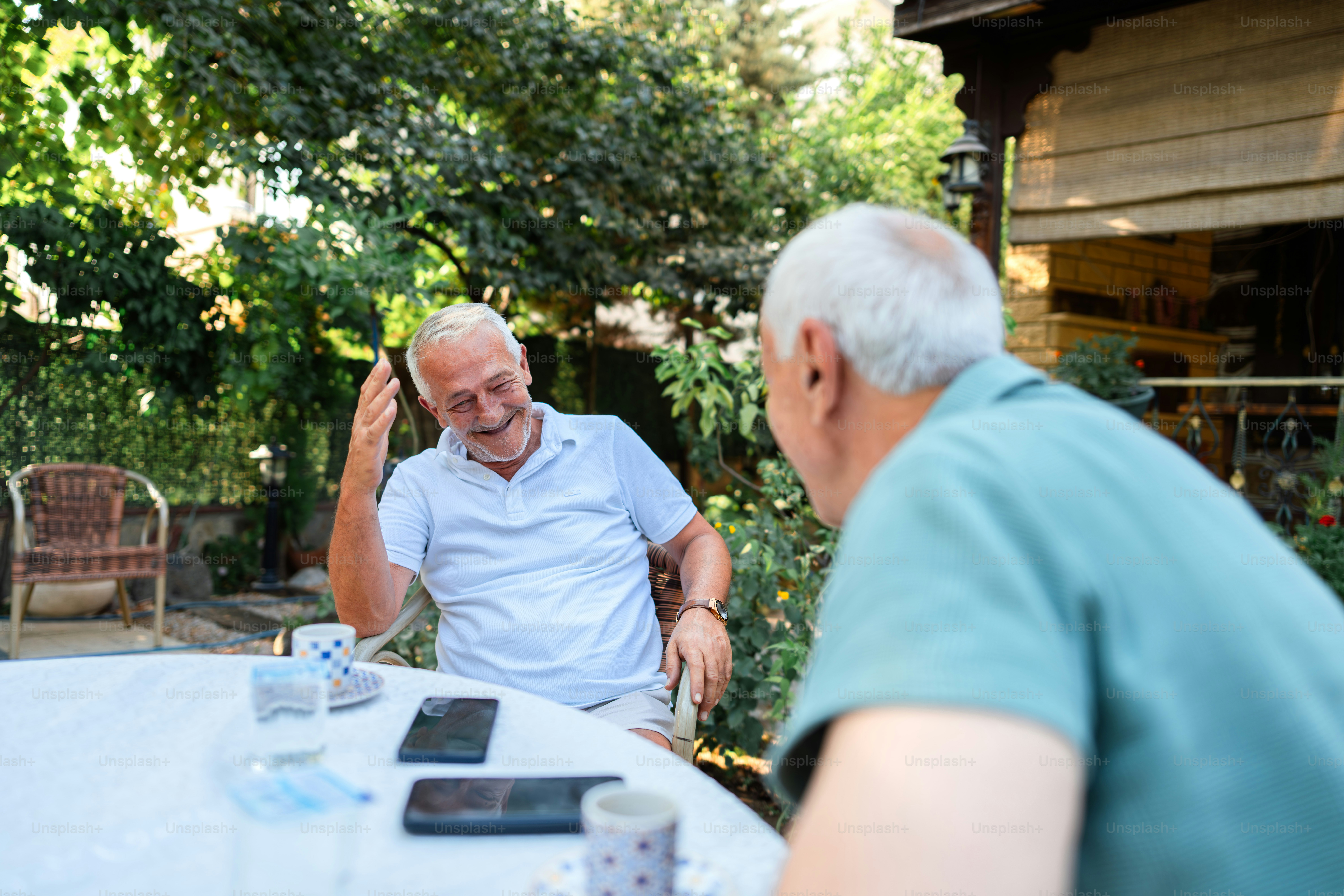 Two older men chat and laugh together outdoors.