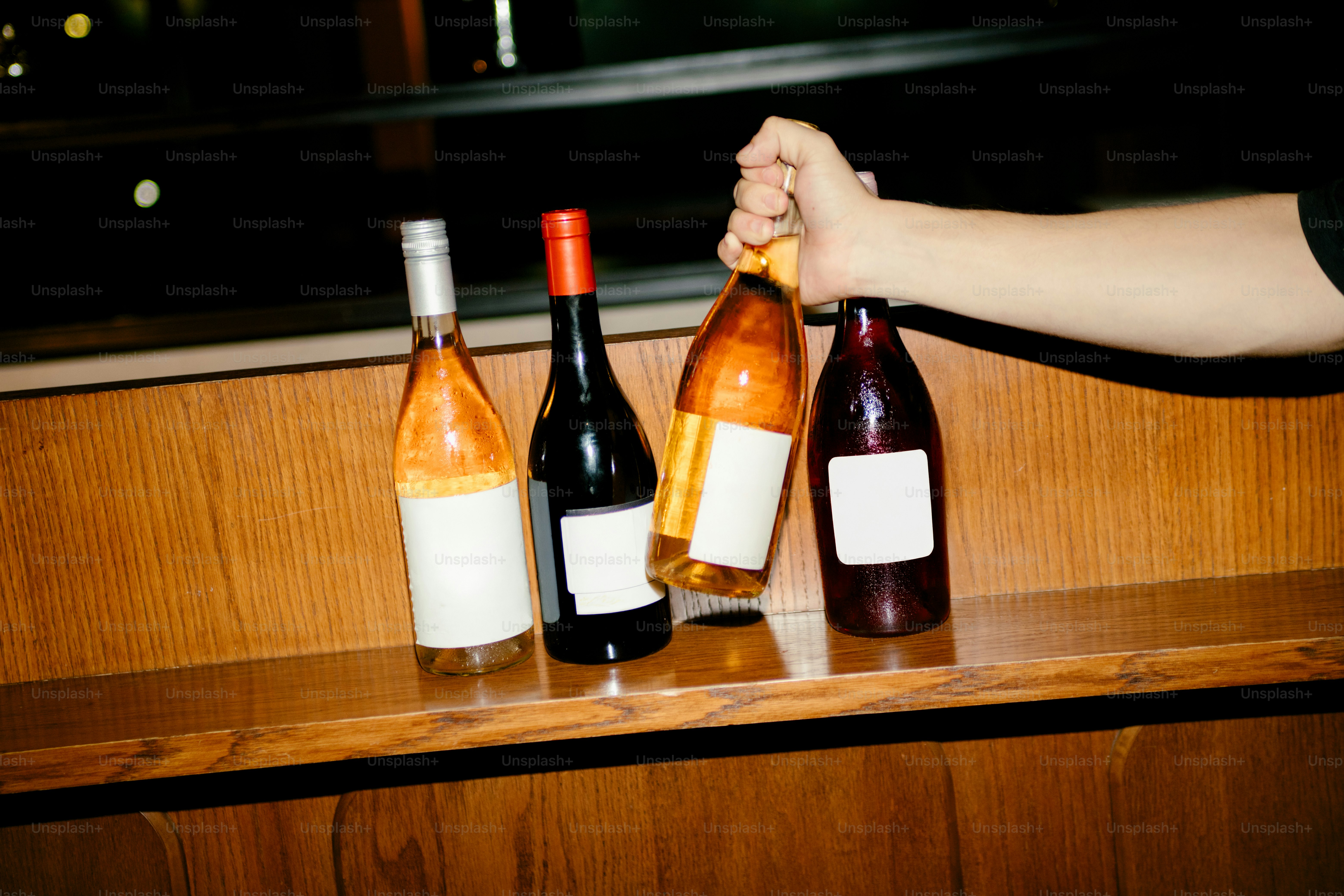 Someone holds a bottle of wine near others.