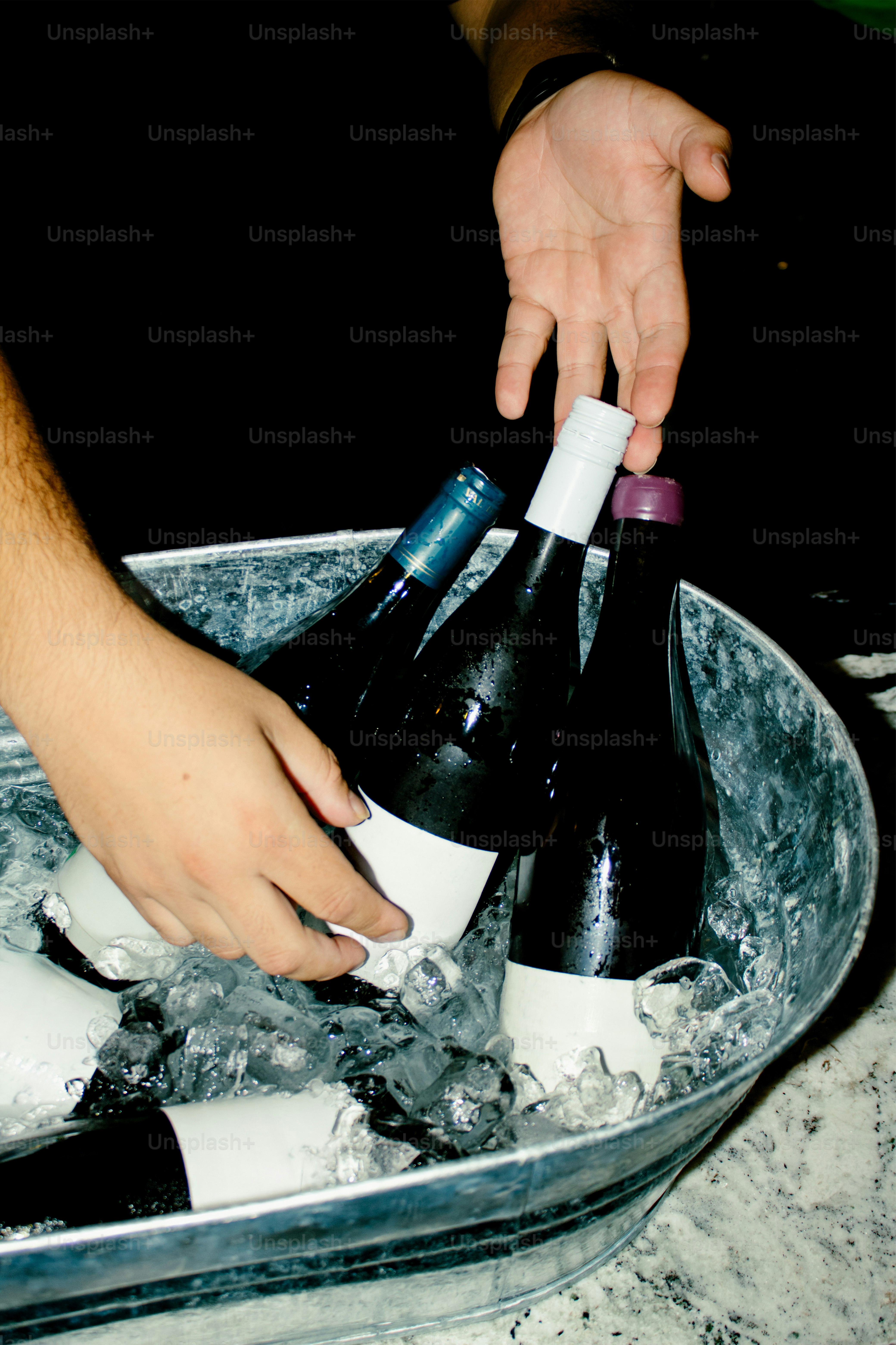 Someone is taking wine bottles from an ice bucket.