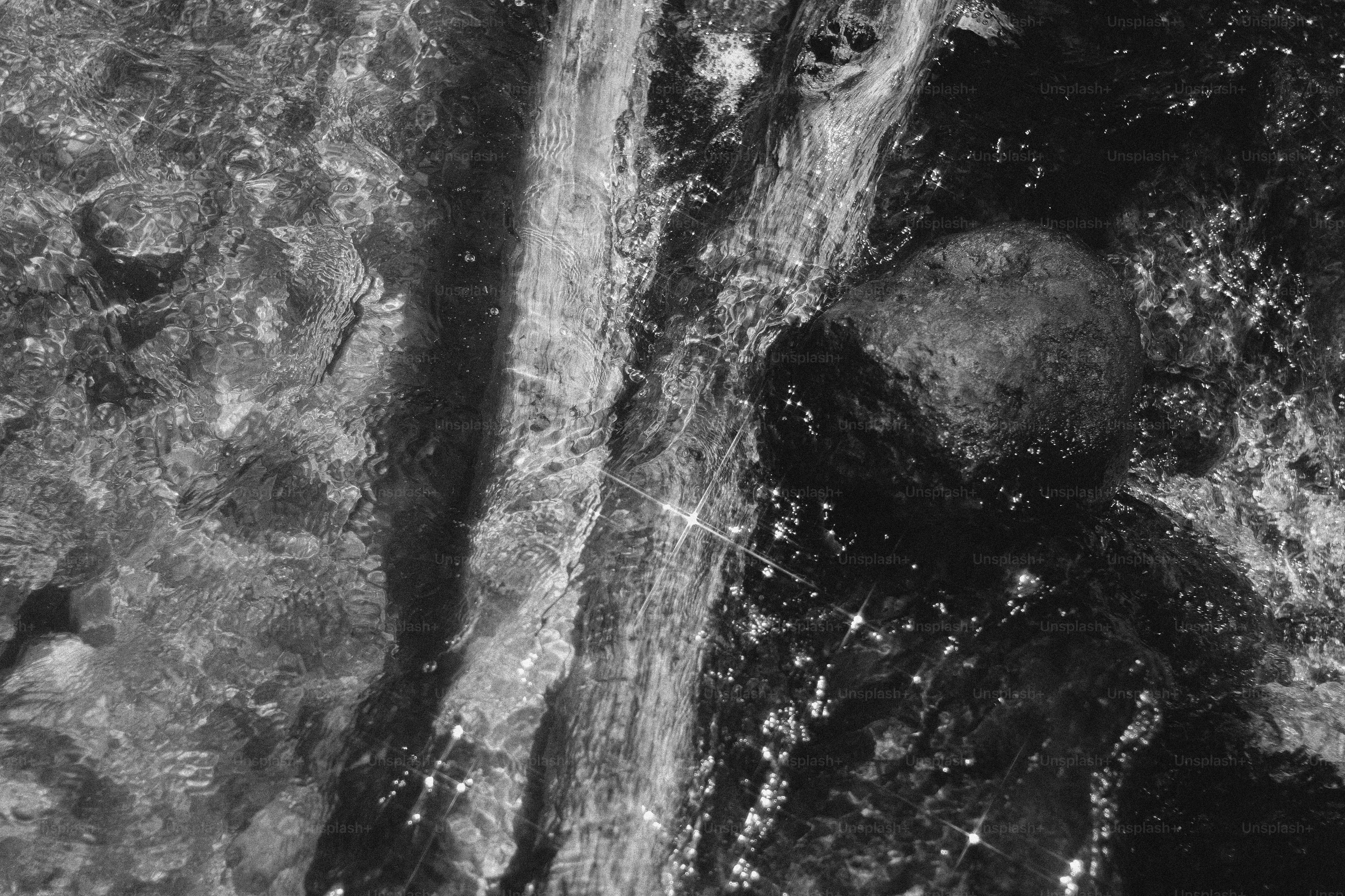 Wasser fließt über Felsen in Schwarz-Weiß.