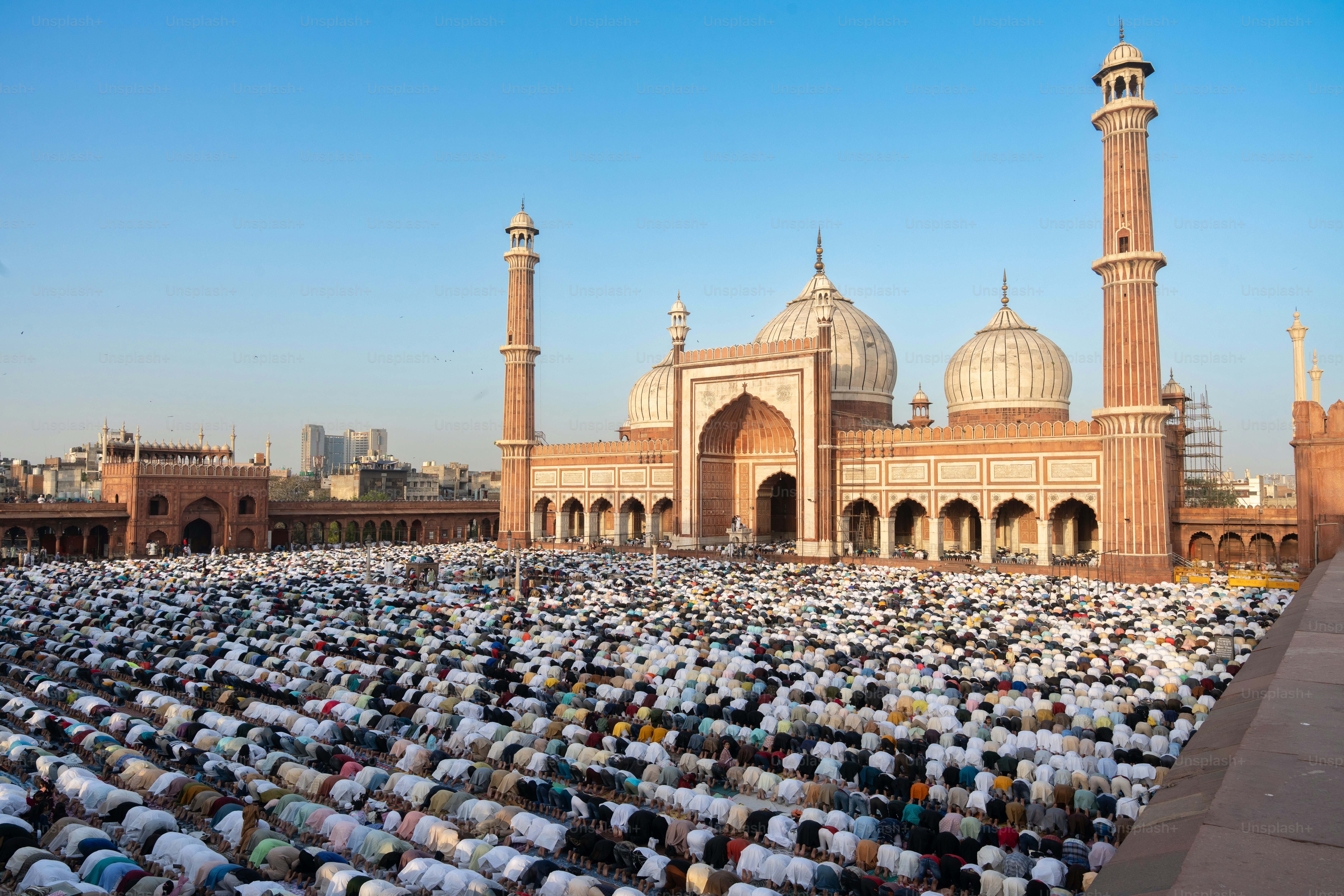 Worshipers pray in front of a grand mosque.