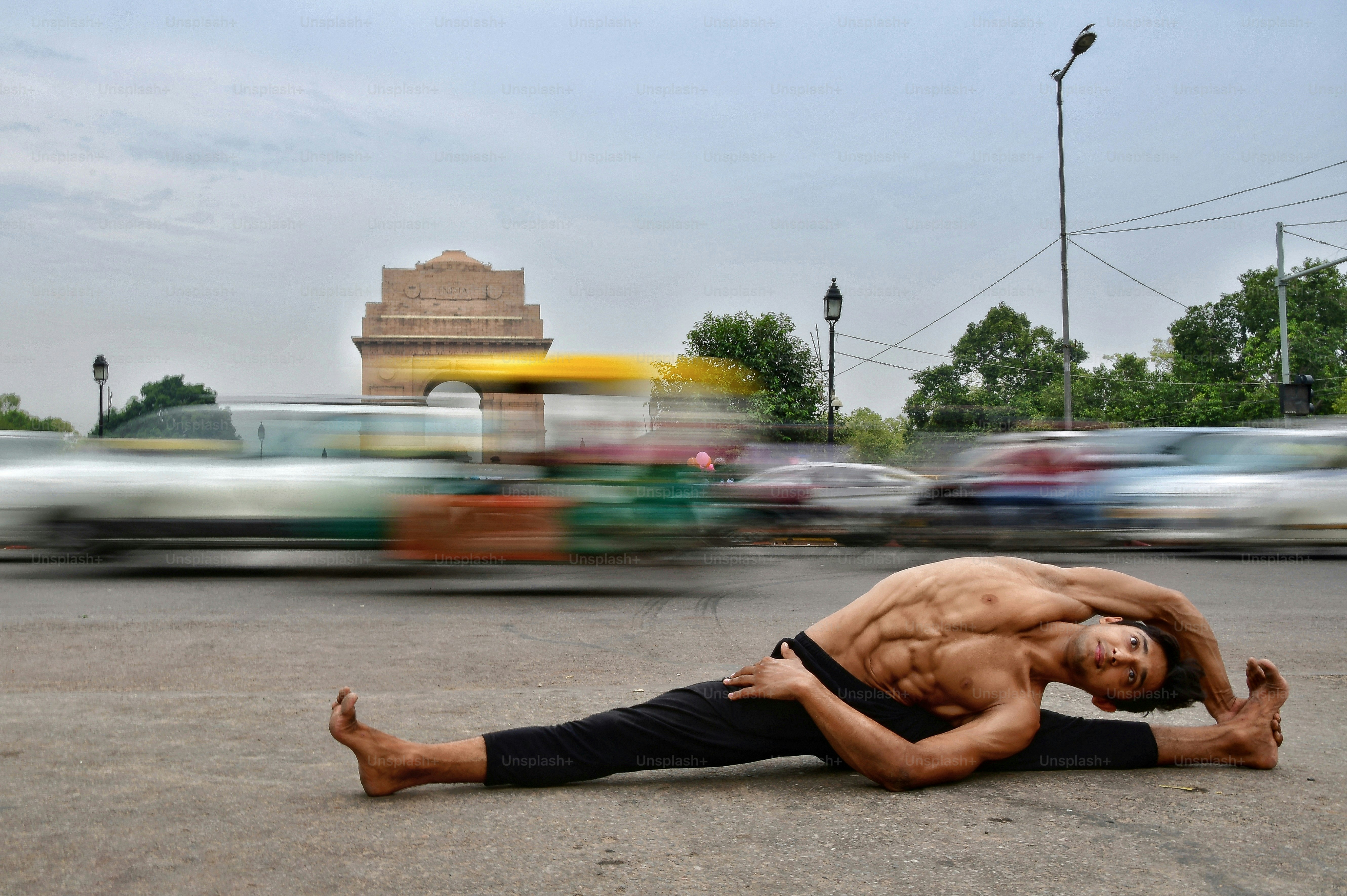 Muscular man does yoga pose in the street.