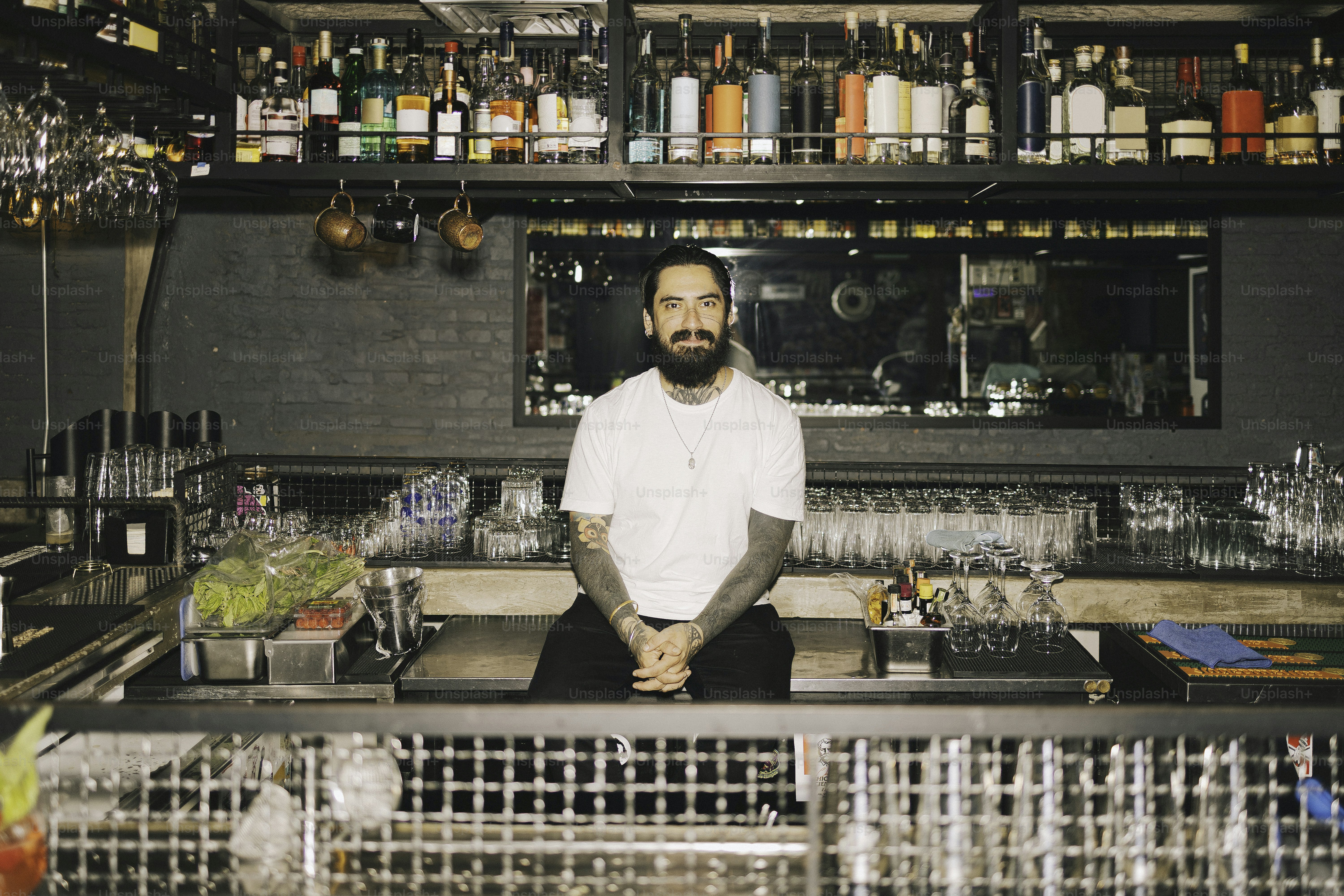 A bartender poses in front of his bar.