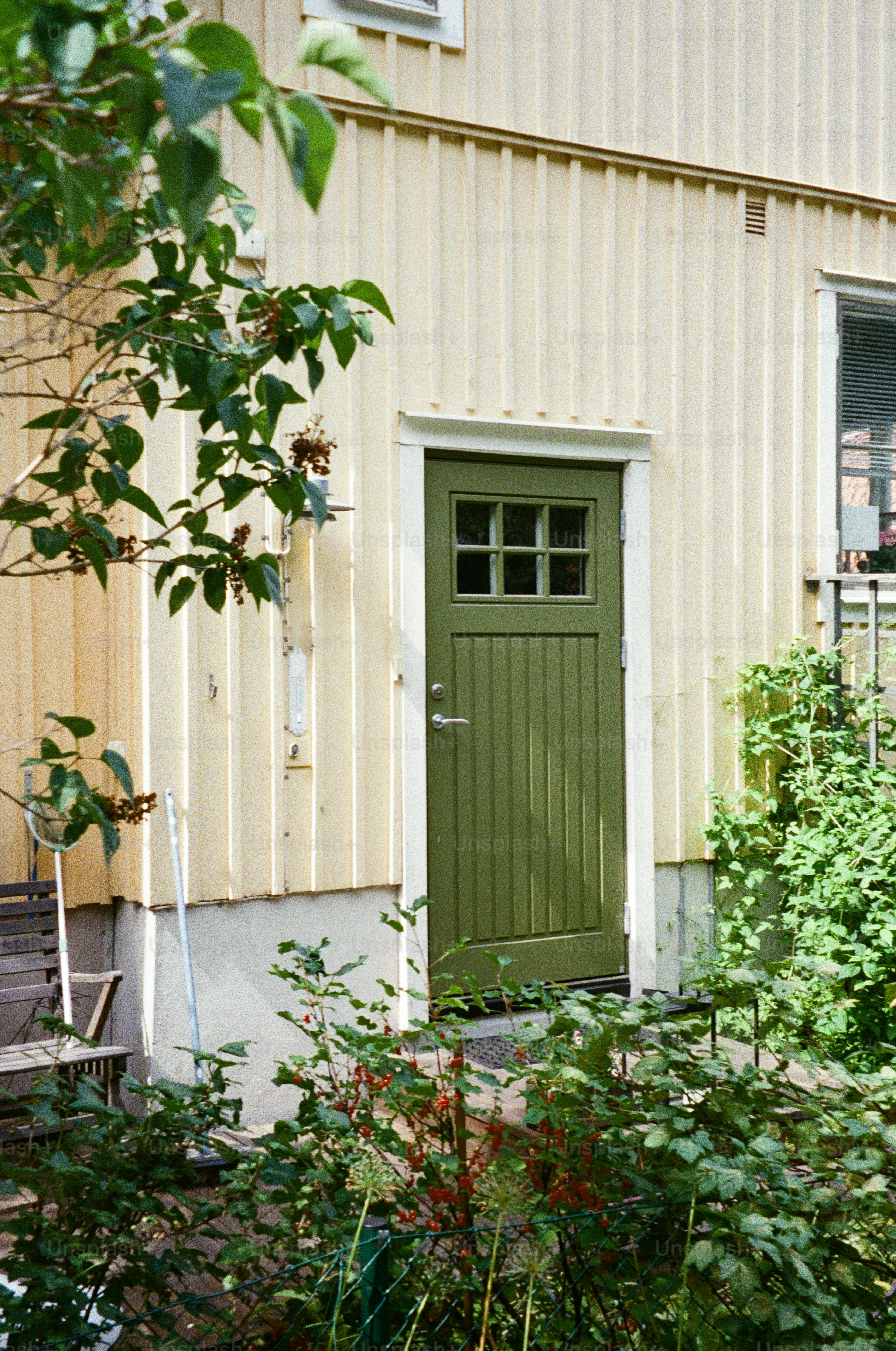 A green door is set against a yellow wall.