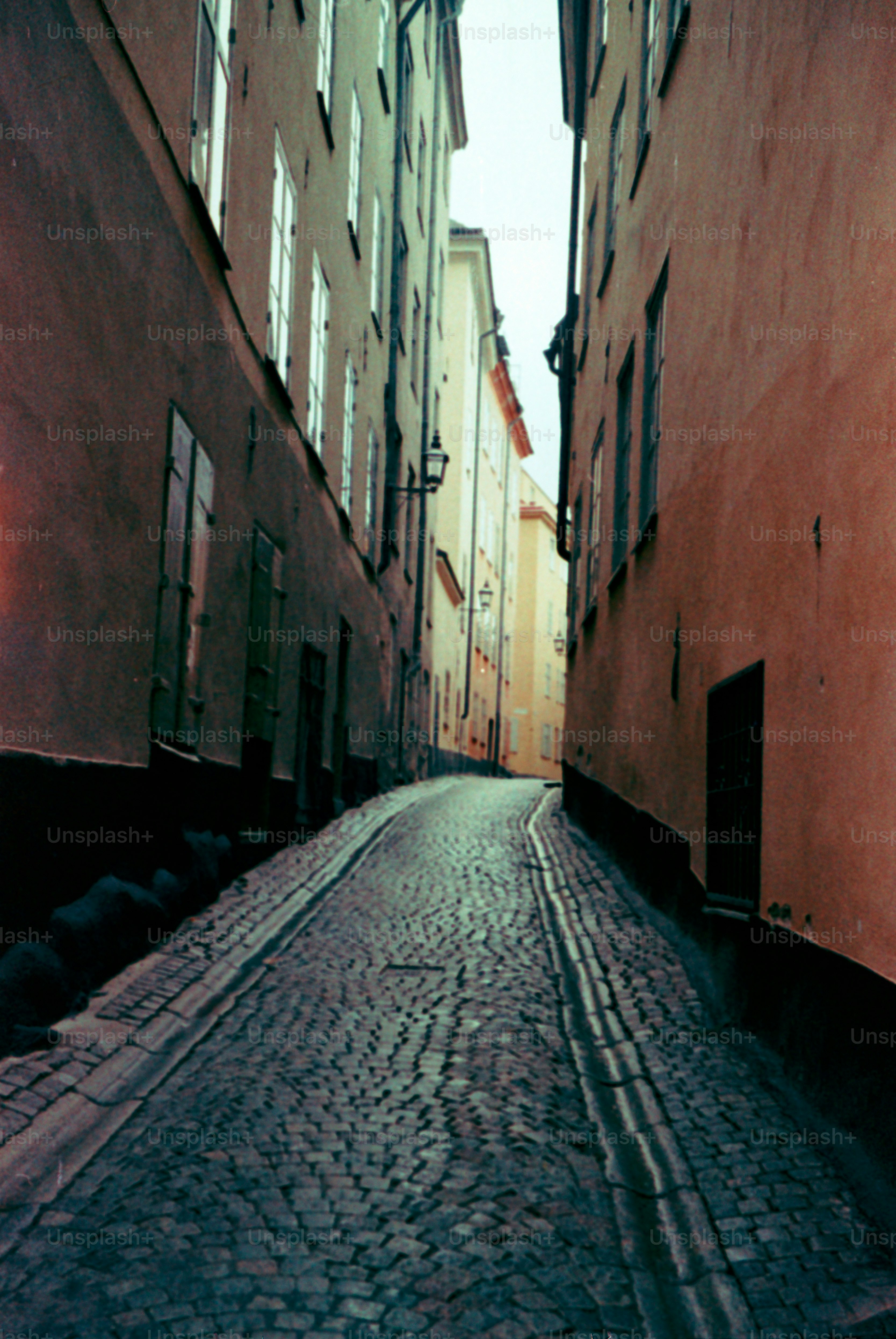 A cobblestone street winds between tall buildings.