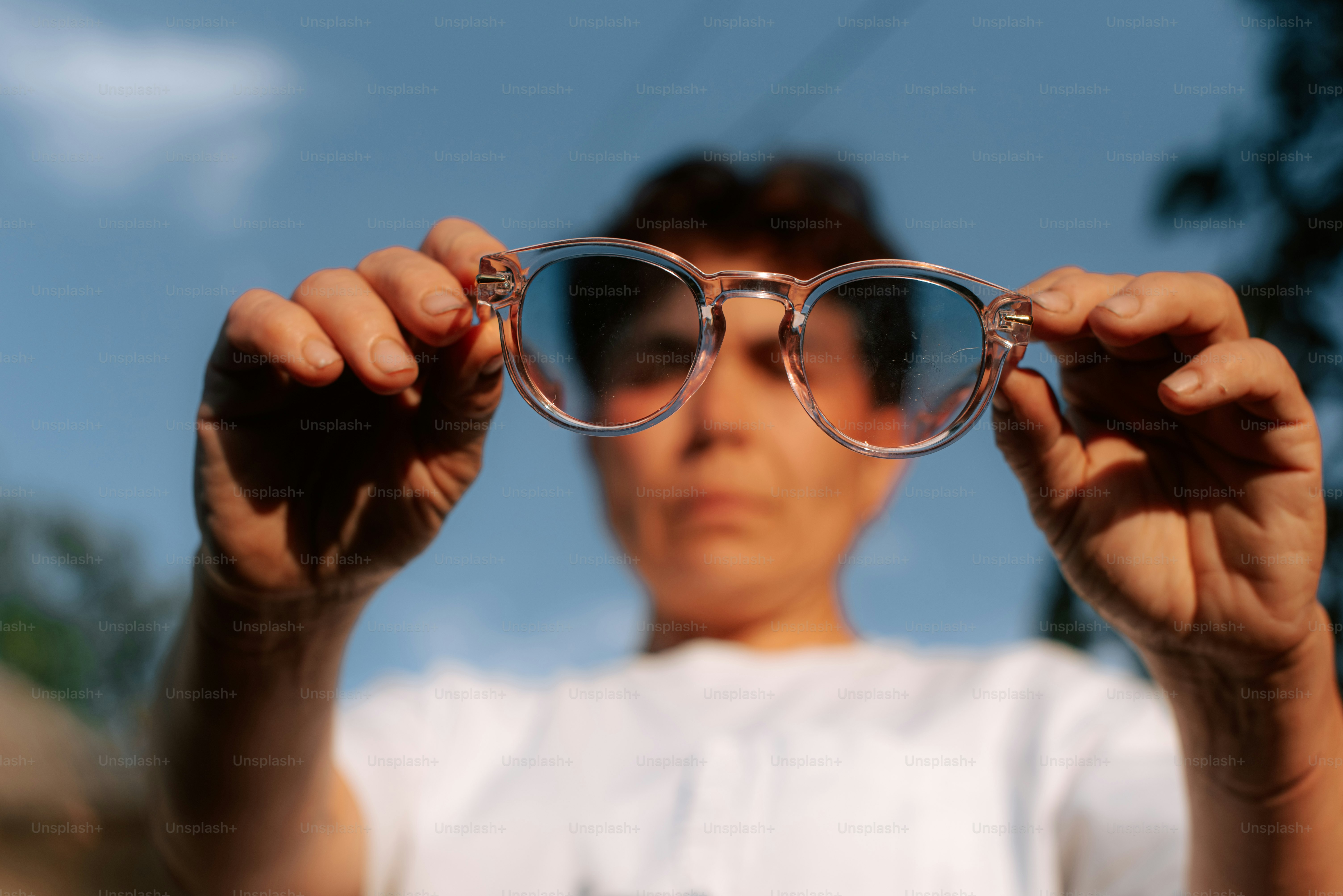 Une personne brandit des lunettes de soleil avec des verres bleus.