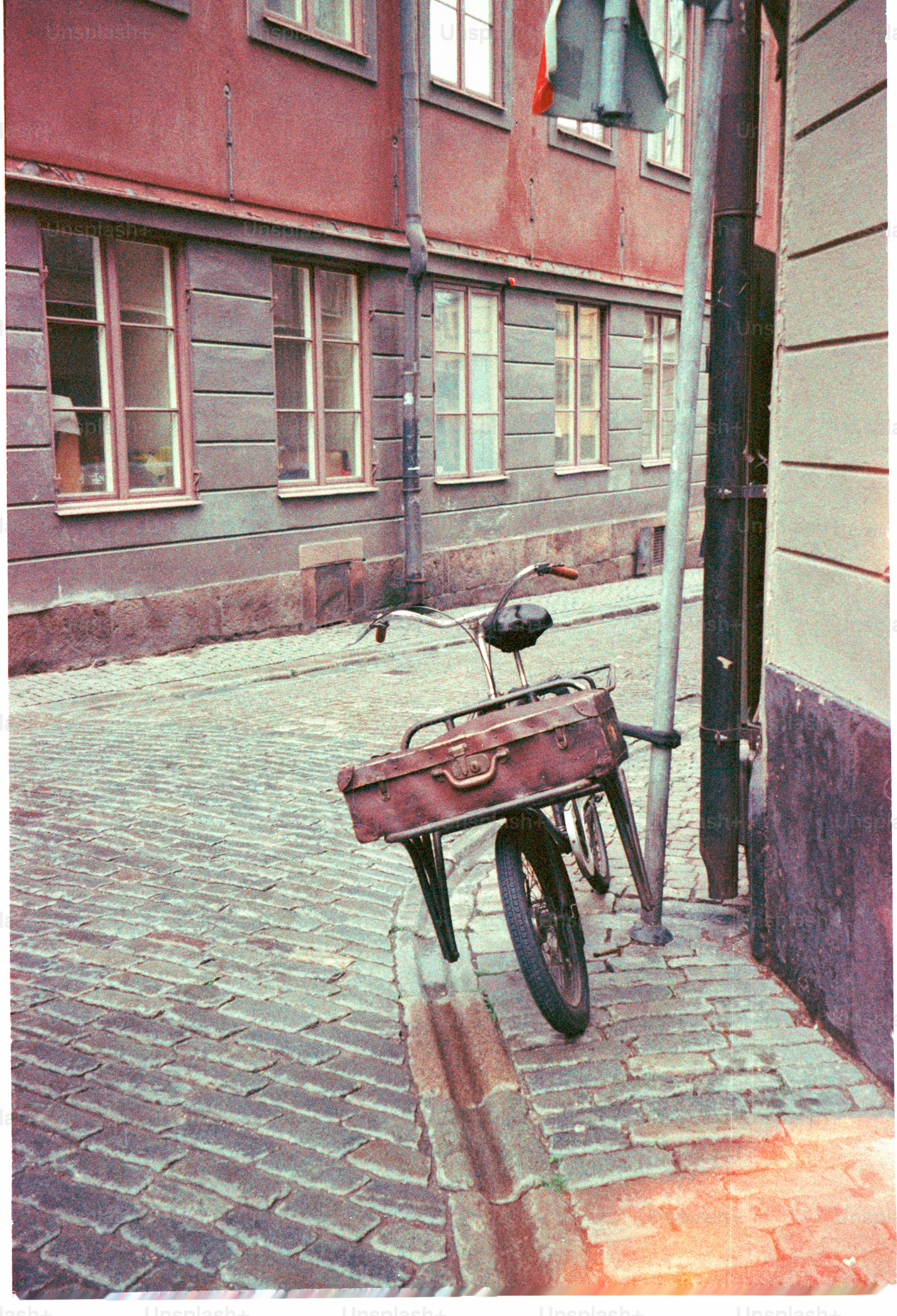 Bicycle with a suitcase parked on a cobbled street.