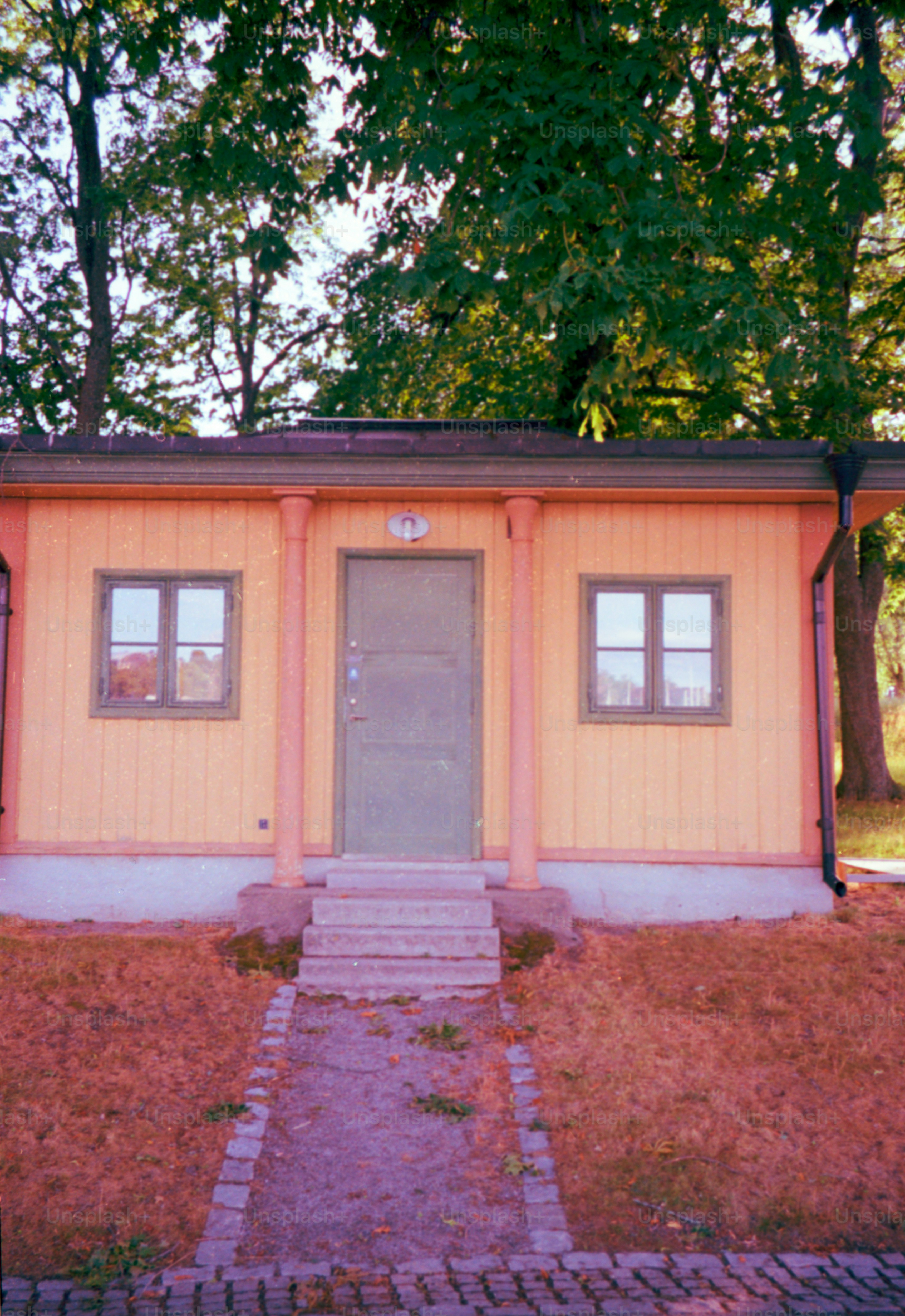 A small, yellow building with a door and two windows