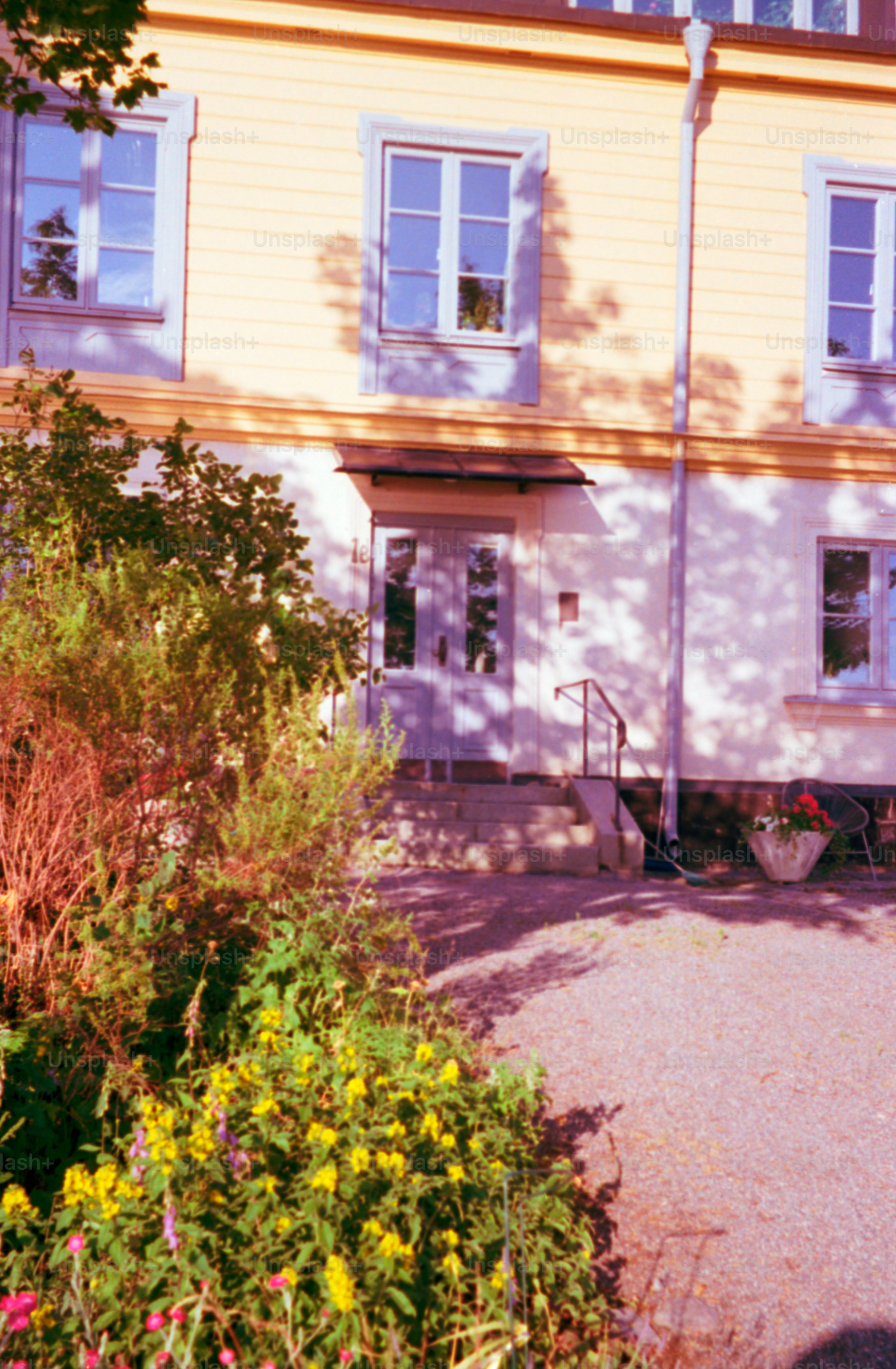 An old, yellow building with a beautiful garden.