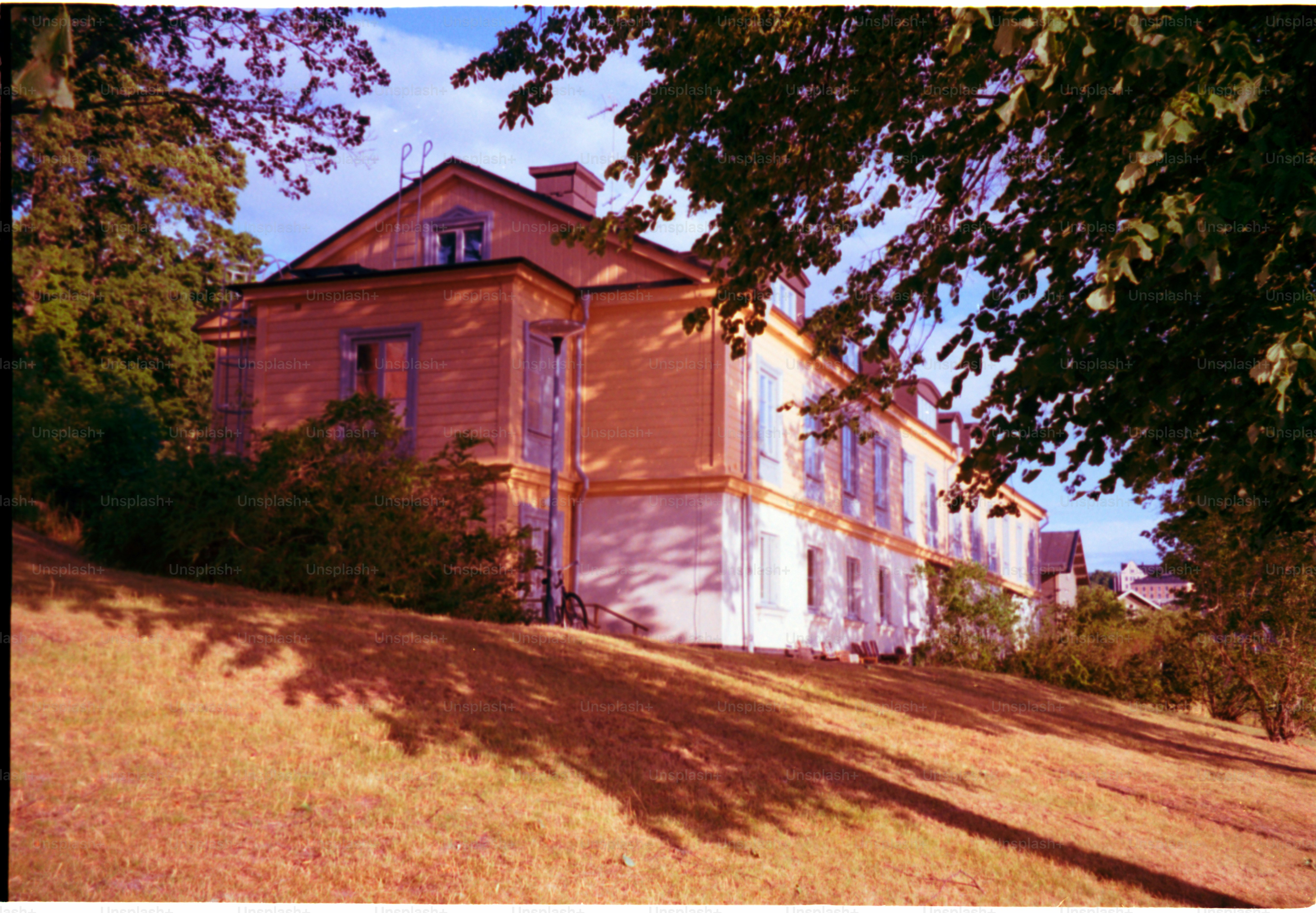 A beautiful yellow house sits on a hill.
