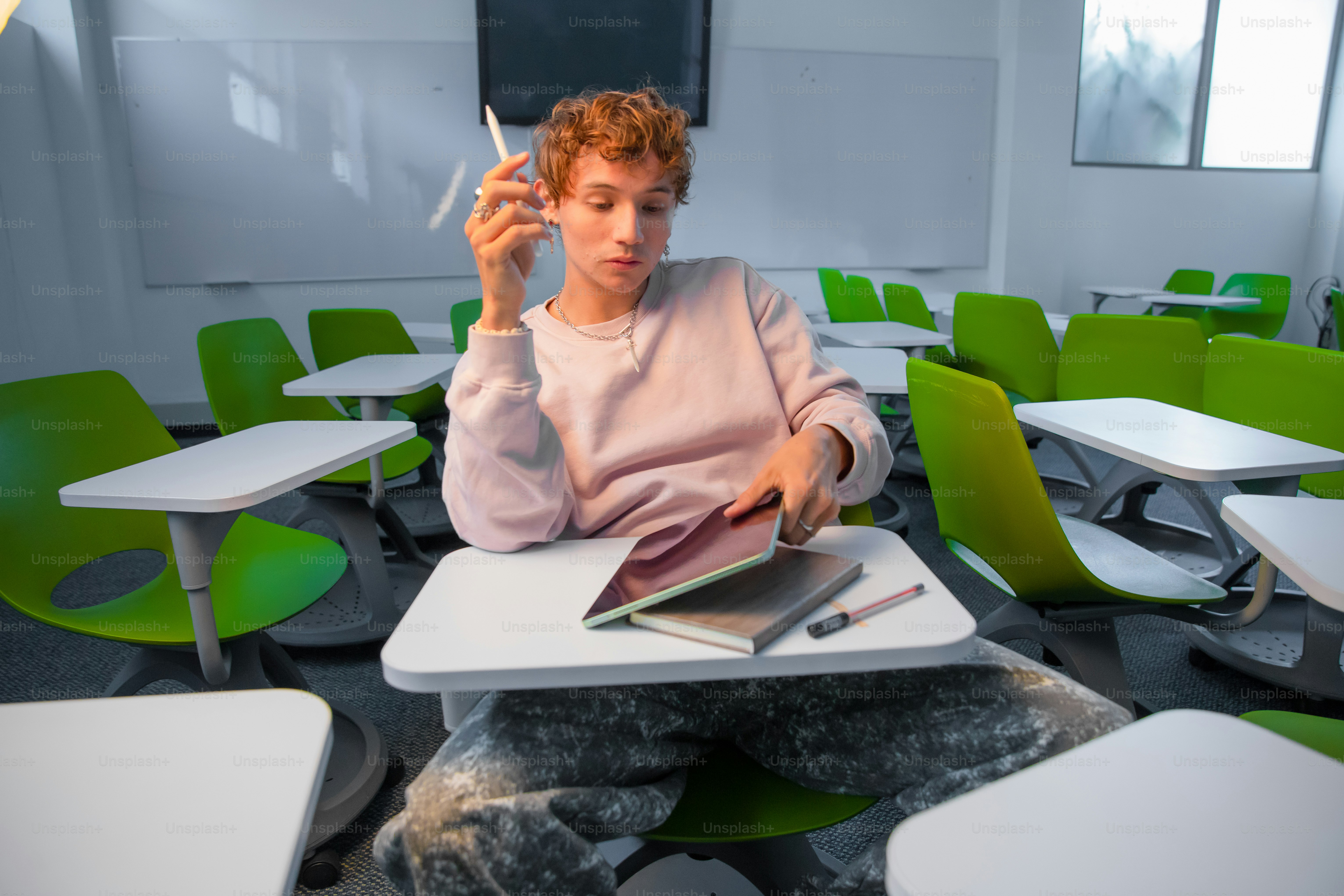 Student sits in a classroom, looking at their notebook.