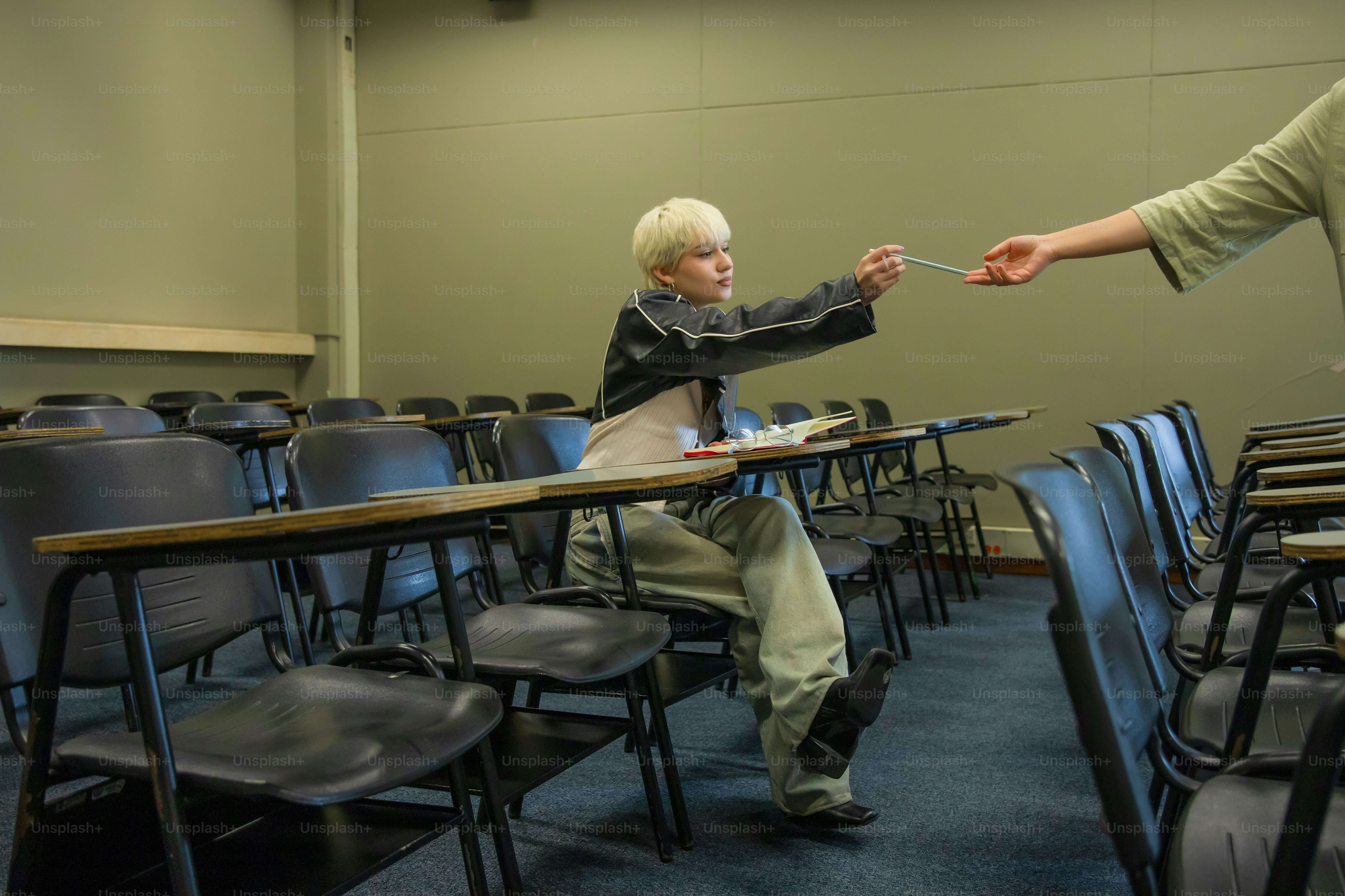 A student receives a pen in an empty classroom.
